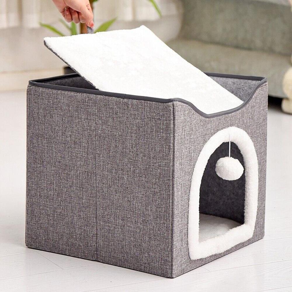 A cat's playhouse made of grey fabric with a soft, white, plush interior. It has a large opening for easy access, a small window, and a hanging toy. - The Magic Toy Shop