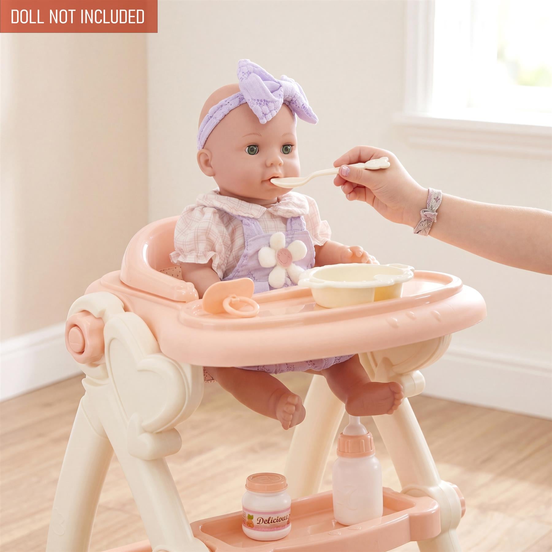 Doll in a pink high chair is being fed; the accessories tray holds bowls and bottles.