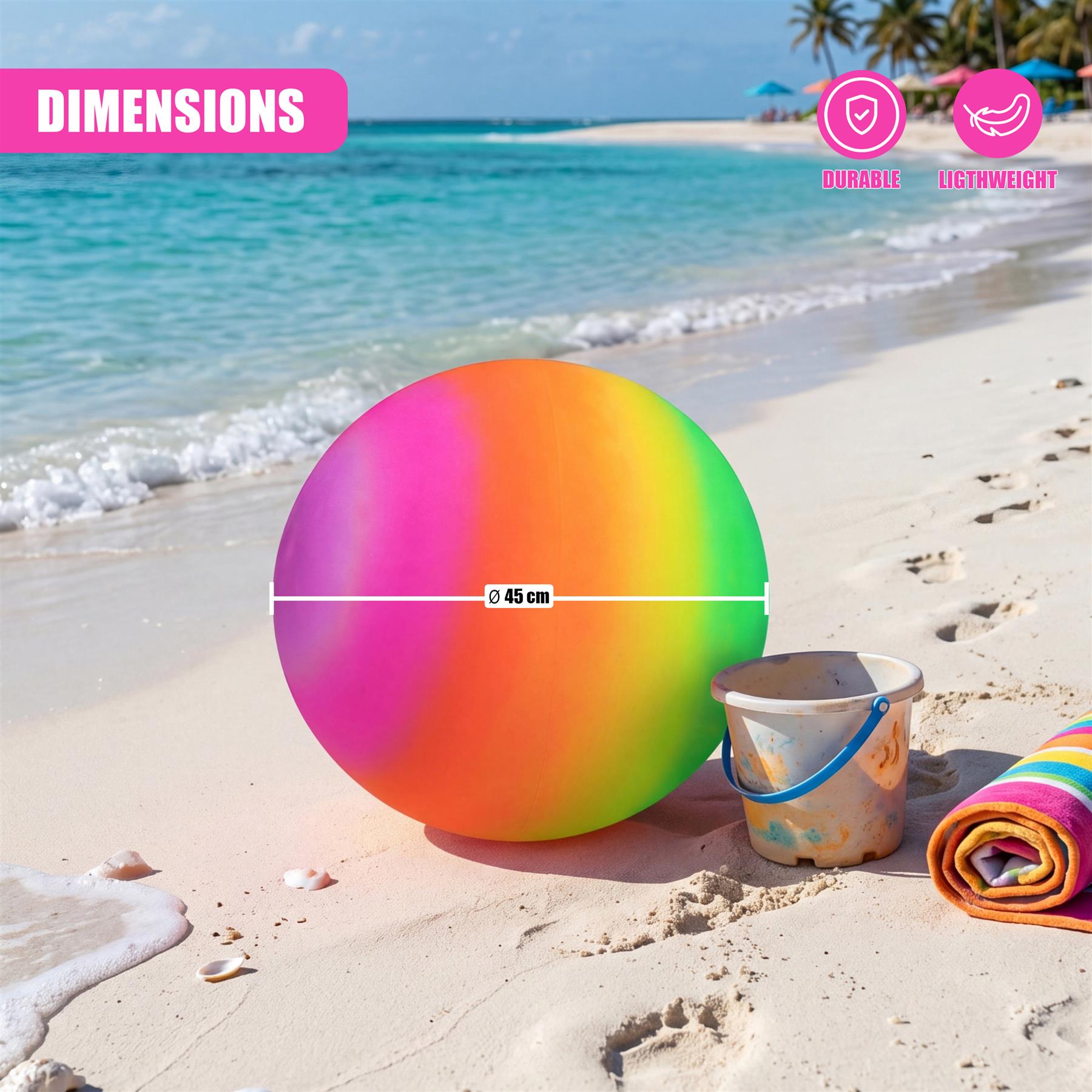 A large, circular ball displaying a color gradient rests on the beach near a small bucket.
