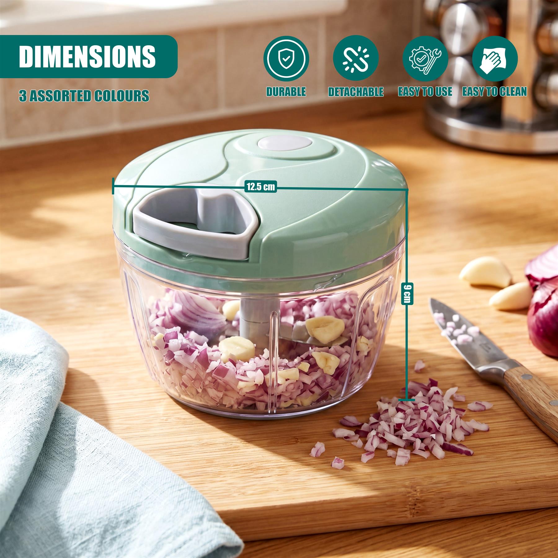 A green manual chopper containing chopped red onions rests on a wooden cutting board near a knife.