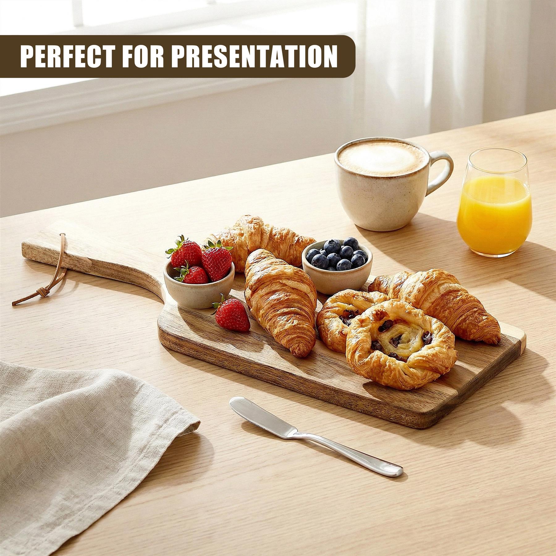 Acacia wood board displays croissants, strawberries, blueberries, coffee, and orange juice.