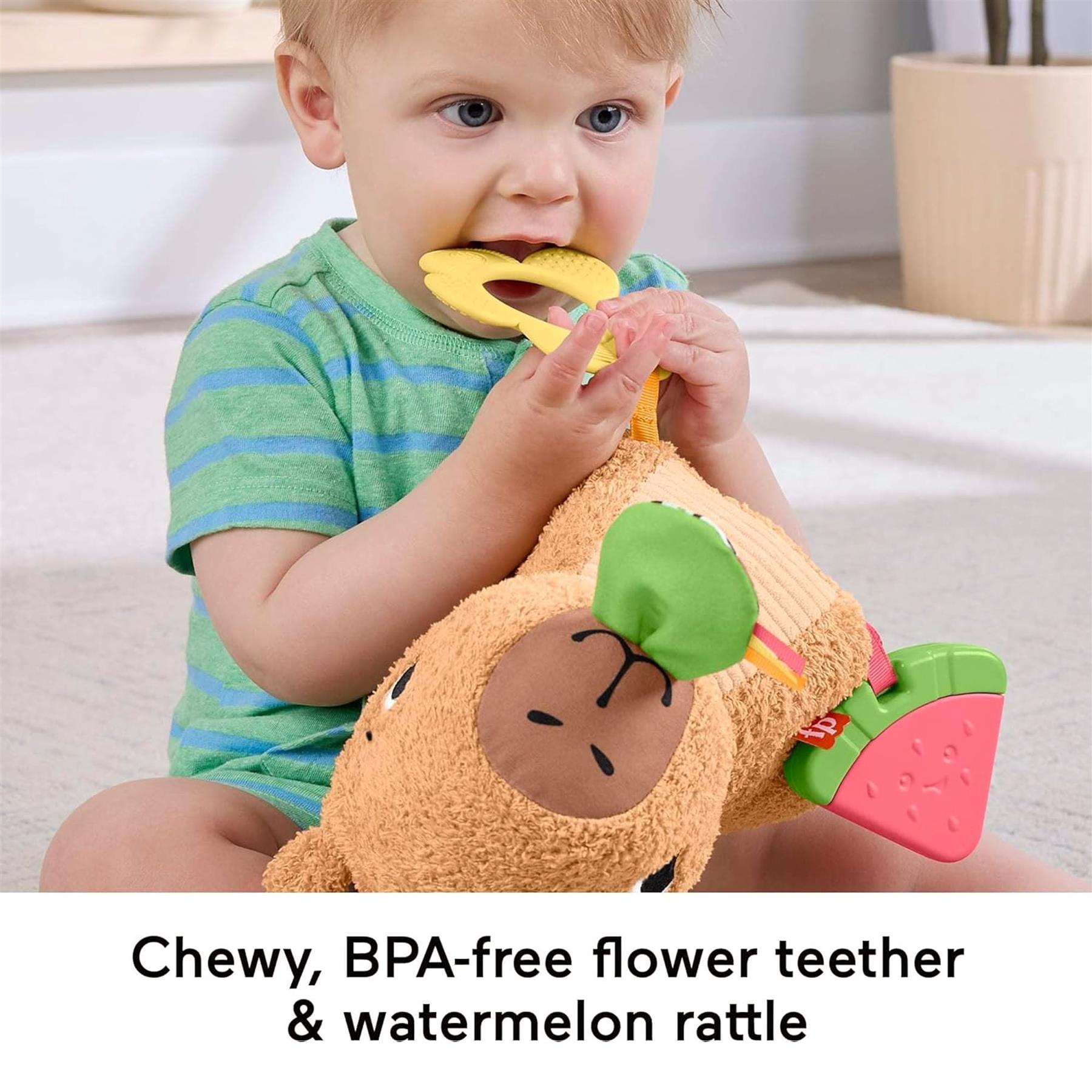 Toddler interacts with a stuffed capybara plush toy featuring yellow flowers and pink watermelon teether attachments.