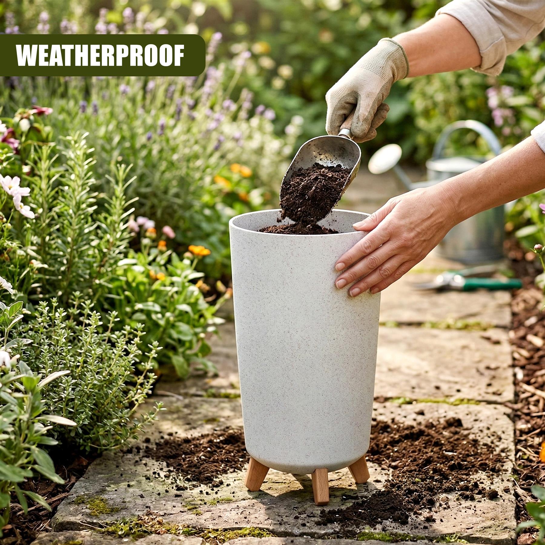 Hands scoop soil into a speckled gray flower pot elevated on four wooden legs in a garden.