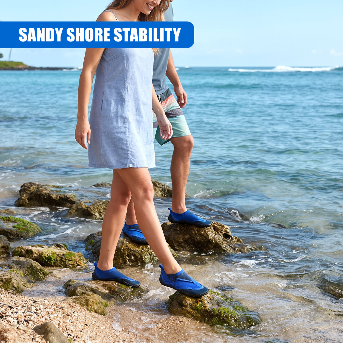 Blue GEEZY aqua shoes protect feet on a sandy shore, with a couple walking in the water