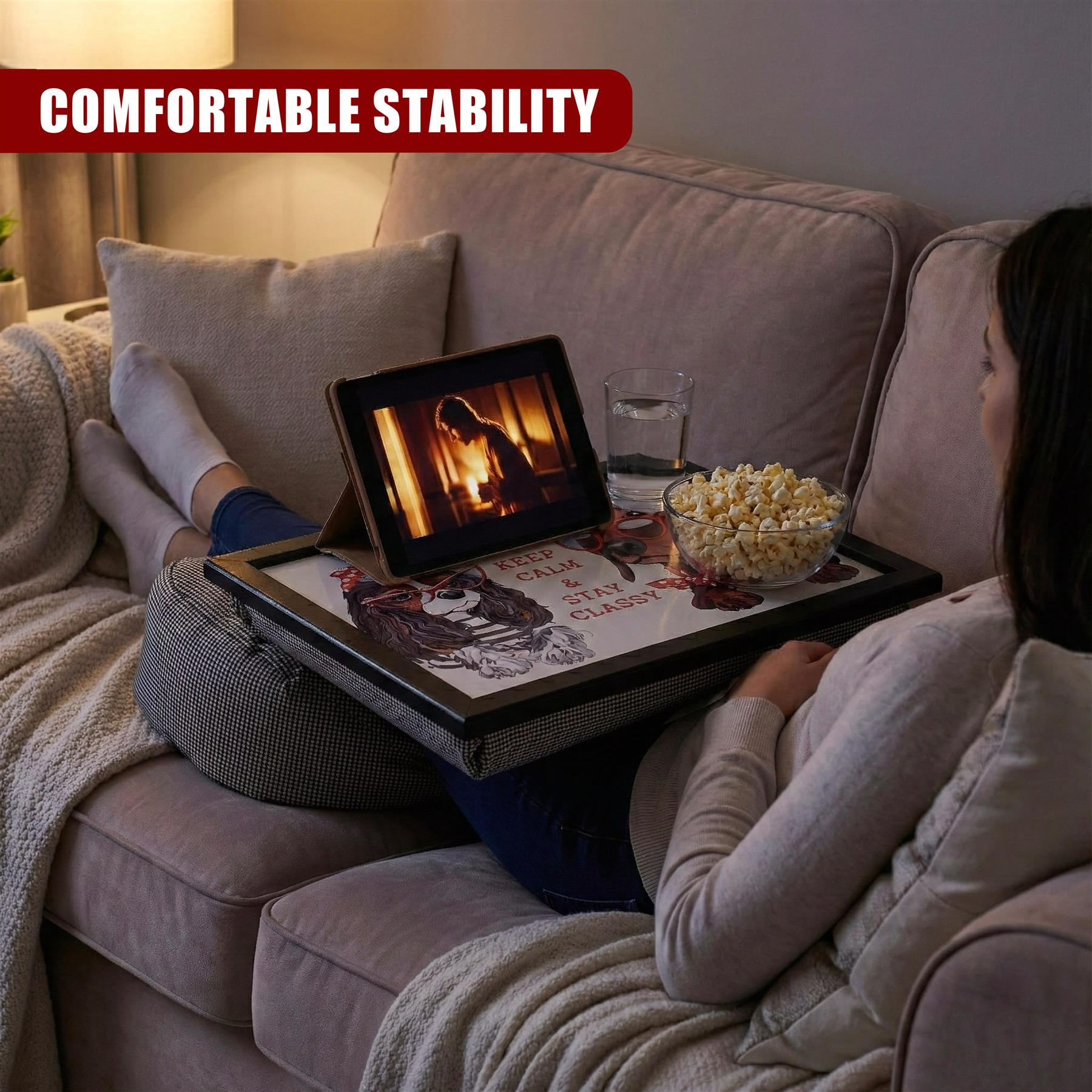 Lap tray placed on a cushion contains a bowl of popcorn, a drink, and a digital picture frame.