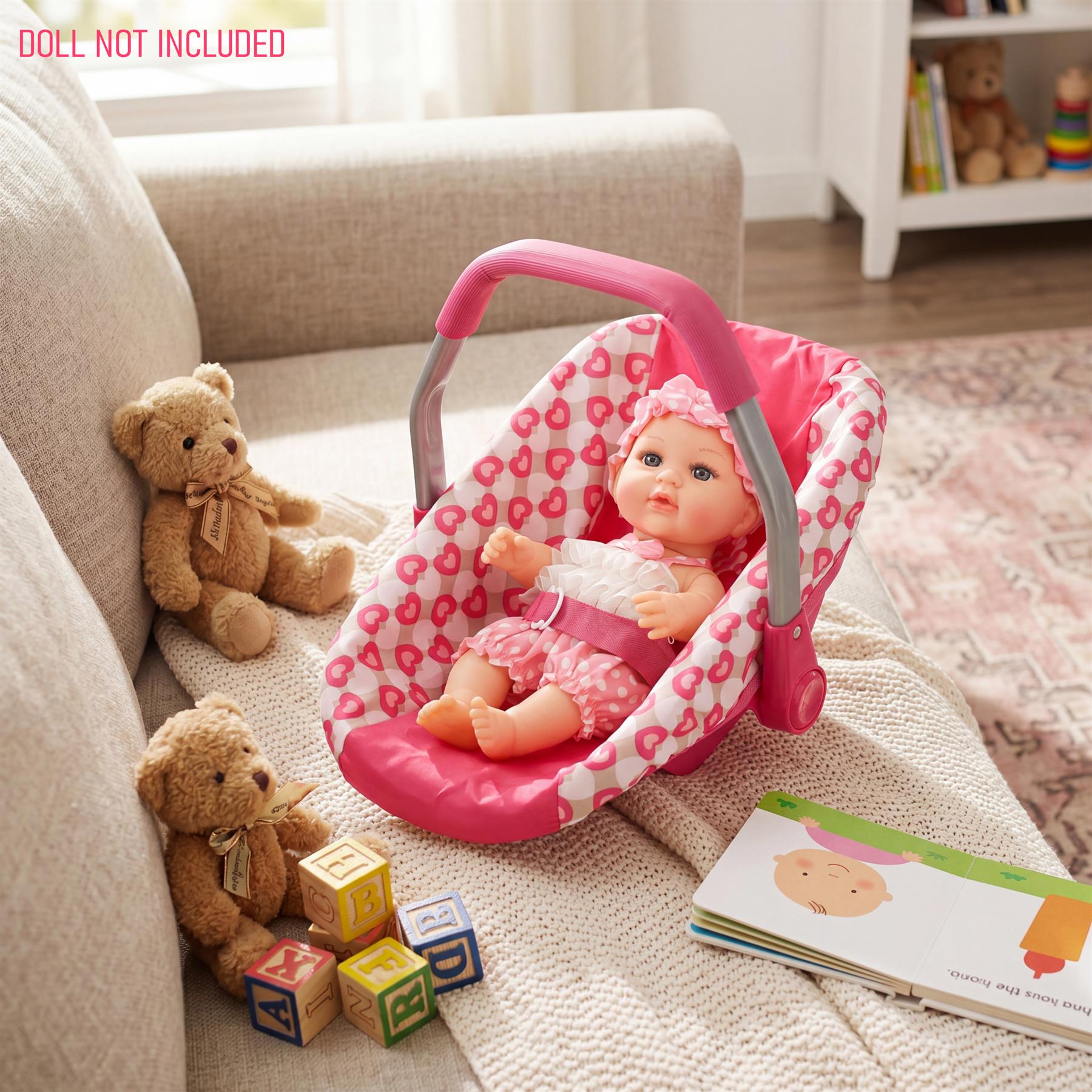 Pink and white car seat with doll, flanked by two teddy bears and alphabet blocks.
