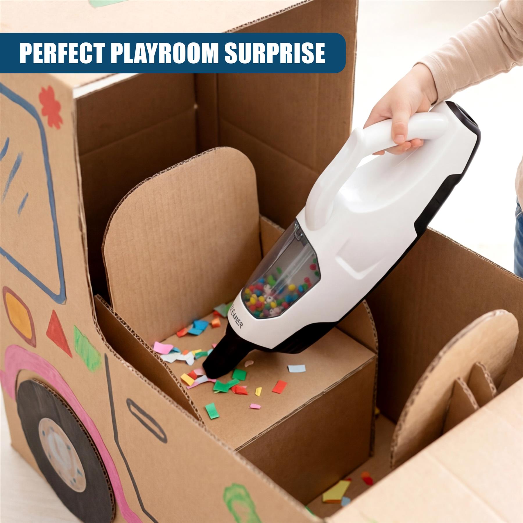 White toy vacuum cleaner rests in a cardboard box with loose colorful pieces.