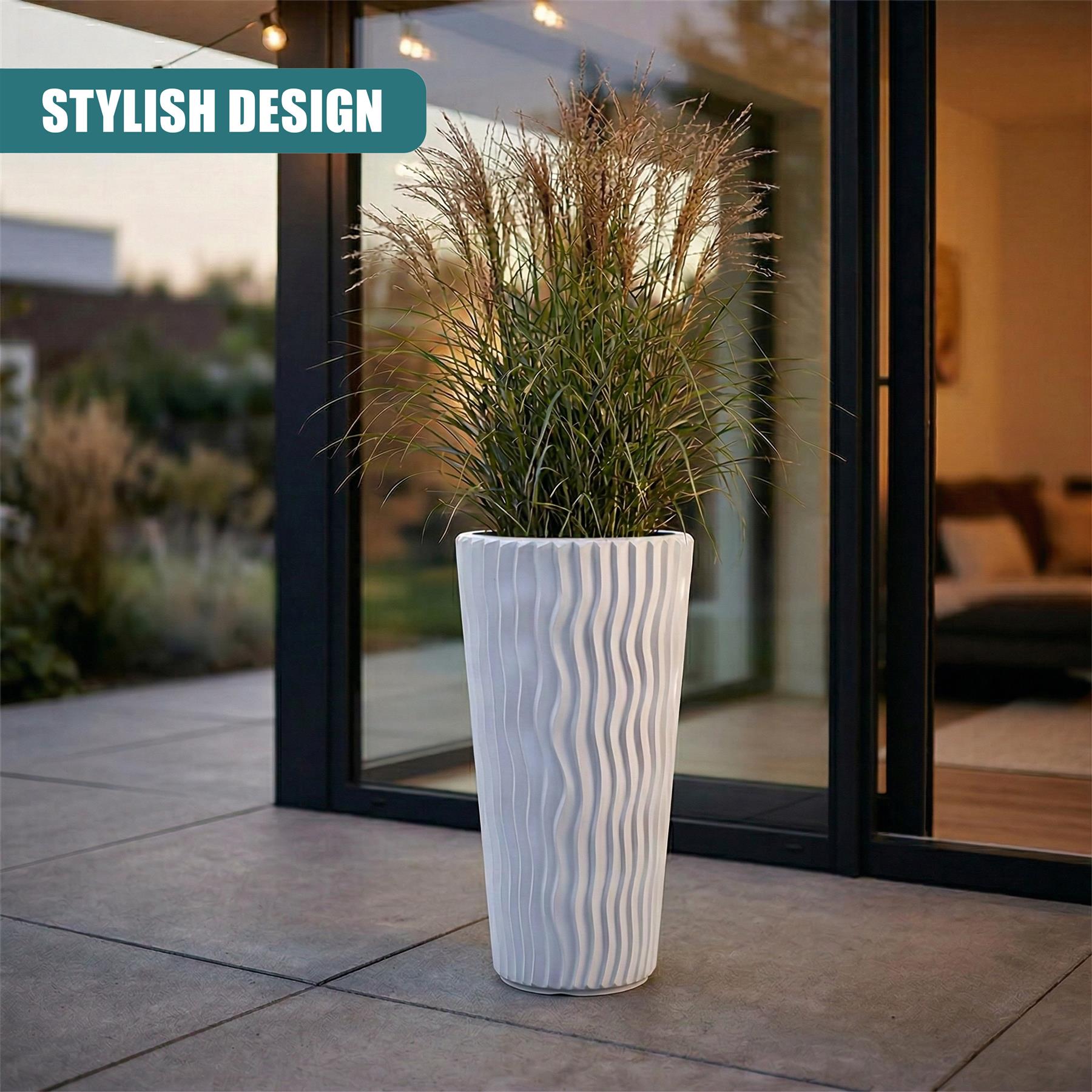 Tall, ribbed white planter holding lush green ornamental grass next to a glass sliding door.