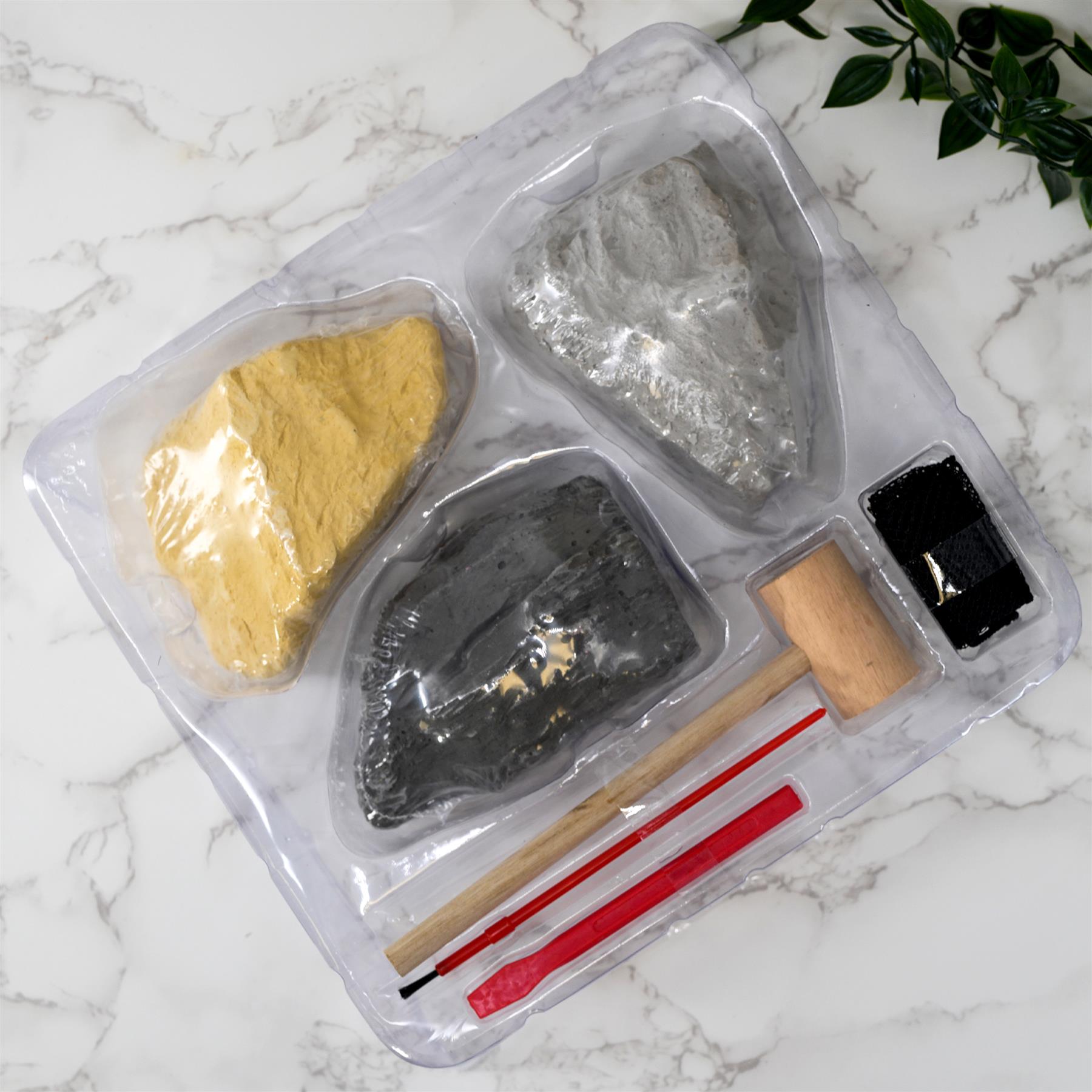 Kit with yellow, gray, and black minerals, a sponge, wooden tools, and small mallet for crafting.