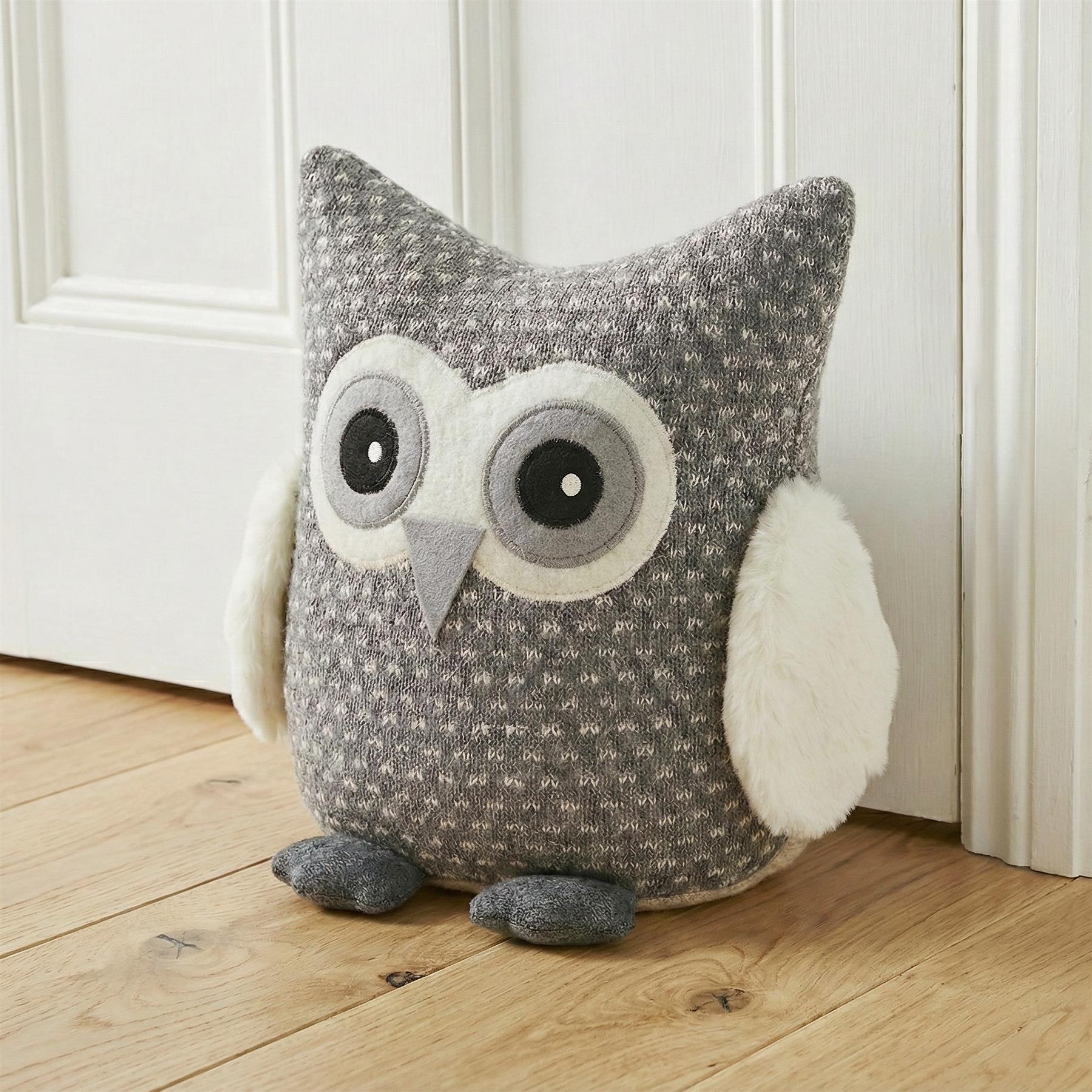 A grey and white owl plush toy sits on a wooden floor in front of a white door. The owl has big, round eyes and a soft, fuzzy texture. It is made of grey and white knitted material. - The Magic Toy Shop