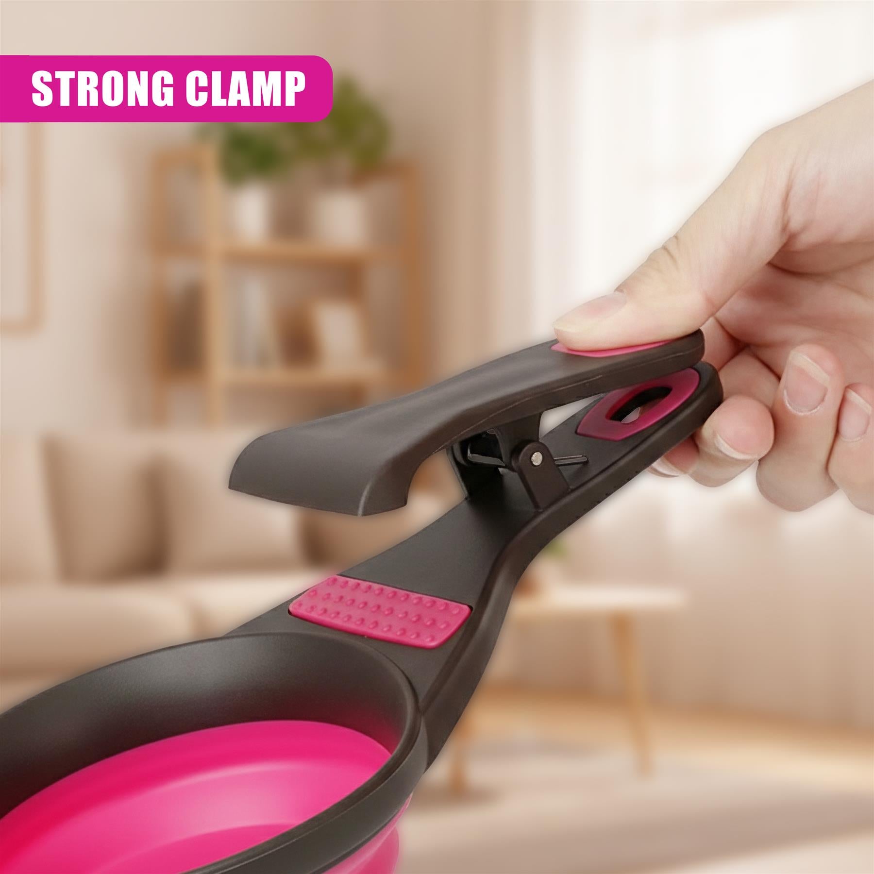 A hand holds a pet food scoop with a dark gray clamp and a contrasting pink interior cup.