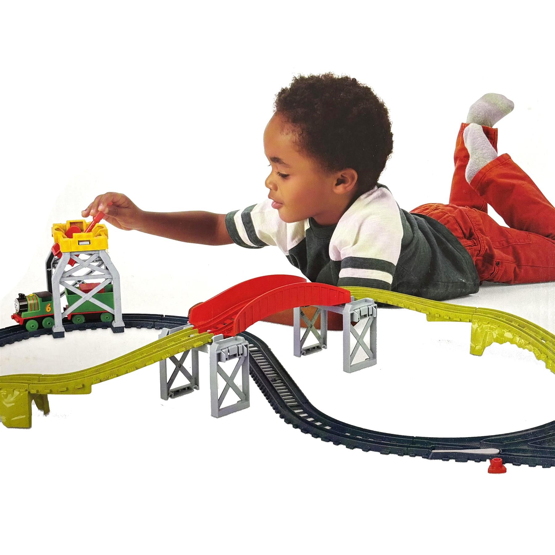 A child interacts with a train set featuring yellow elevated track, a red cargo ramp, and miniature train pieces.