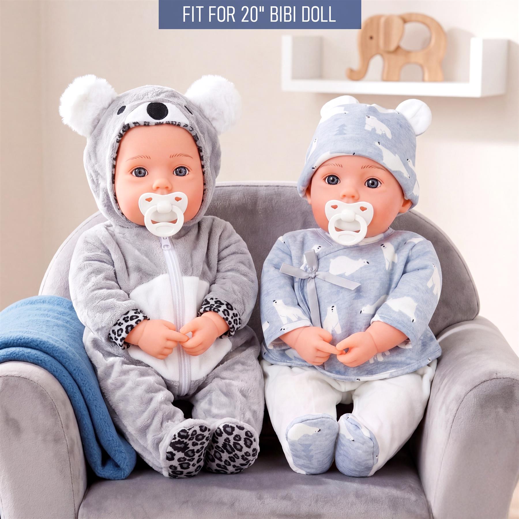 A polar bear styled outfit and a spotted blue outfit are worn by two dolls on a couch.