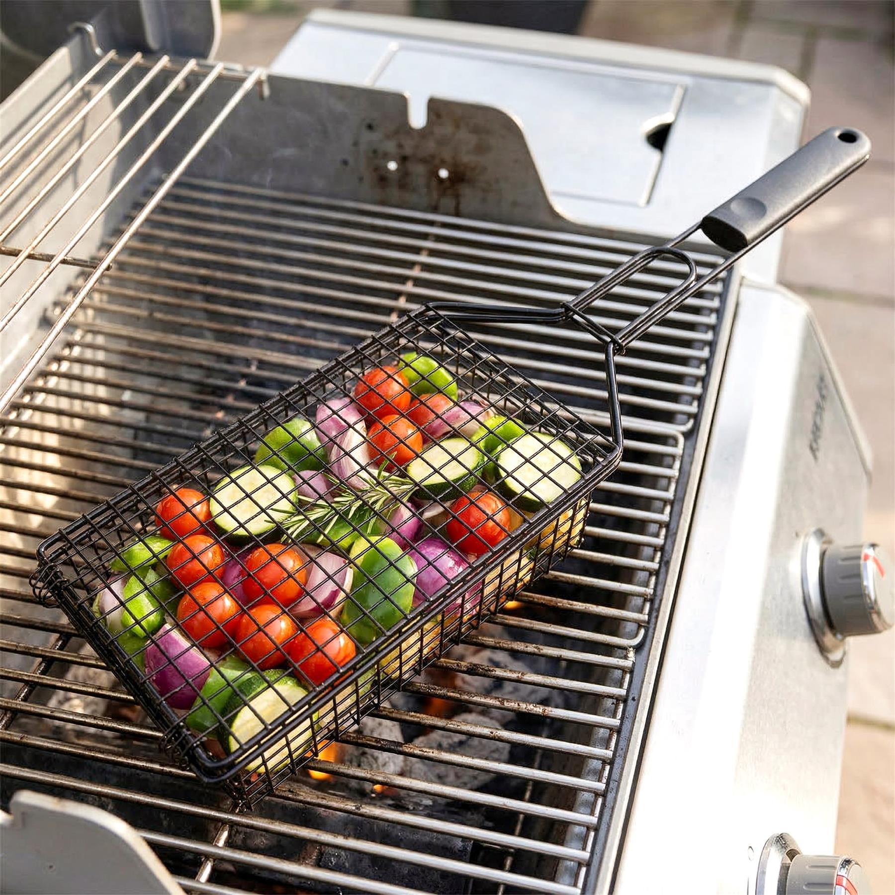 Deep metal grilling basket filled with mixed colorful vegetables rests on the BBQ grate.