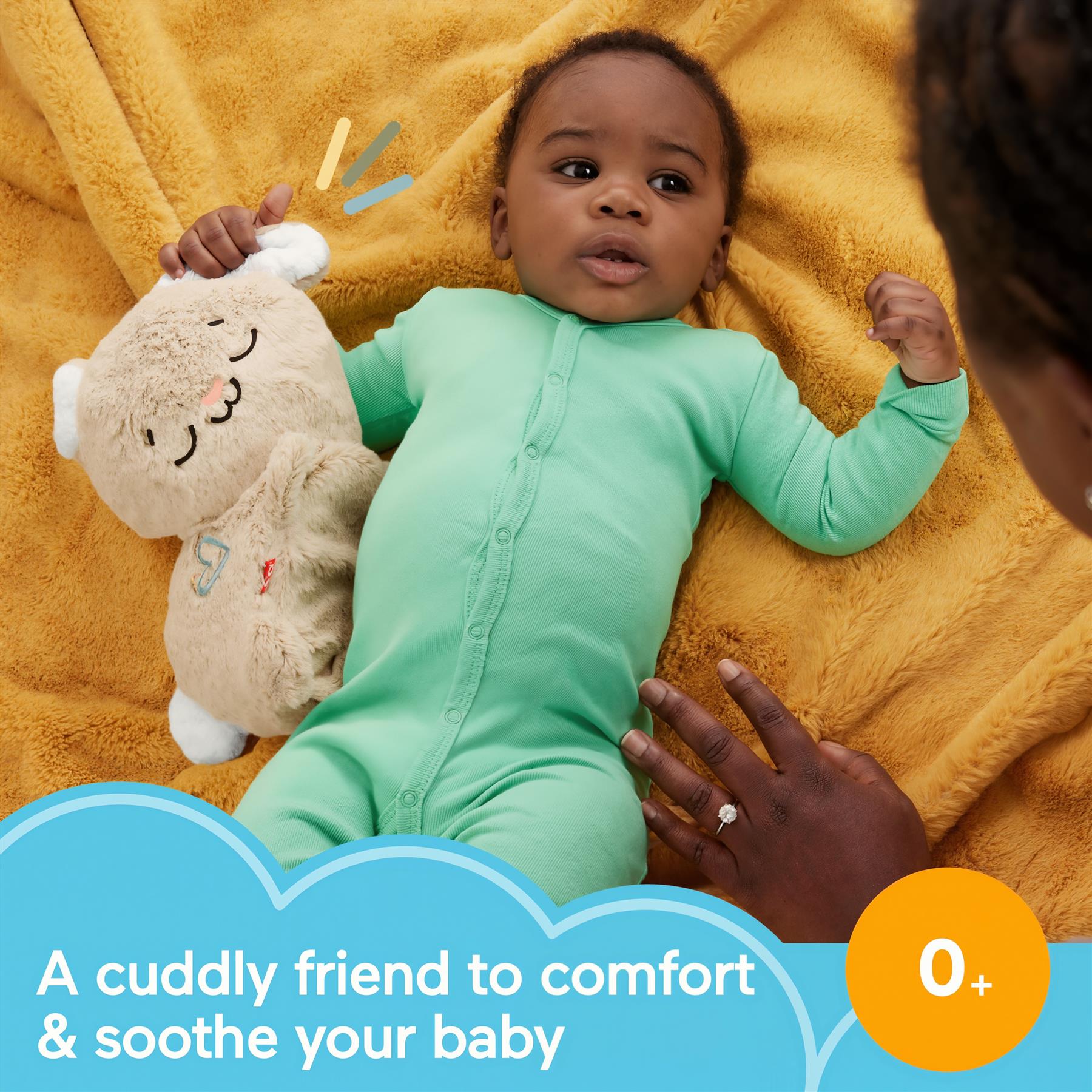 Infant holding a beige bunny plush toy while lying on a yellow blanket.
