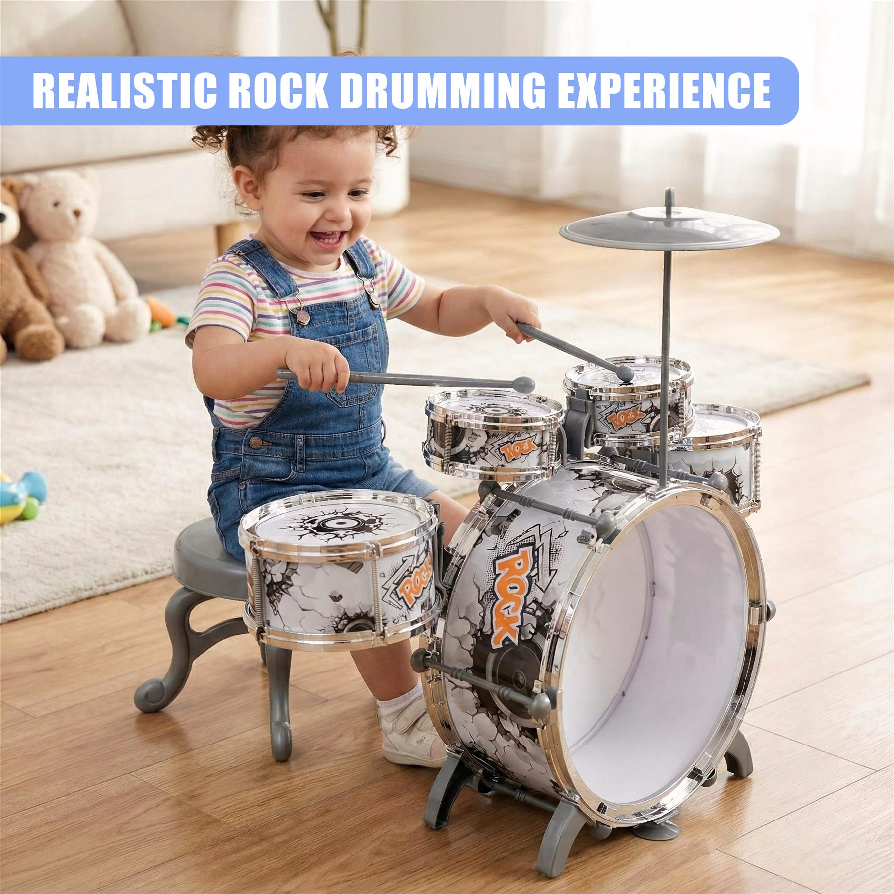 A child sits on a small, grey stool, playing a toy drum set. The drum set has a white and black design with a "ROCK" logo. The child is wearing blue overalls and a striped t-shirt. The background is a living room with a couch and a rug. The child is holding a drumstick and smiling. - The Magic Toy Shop
