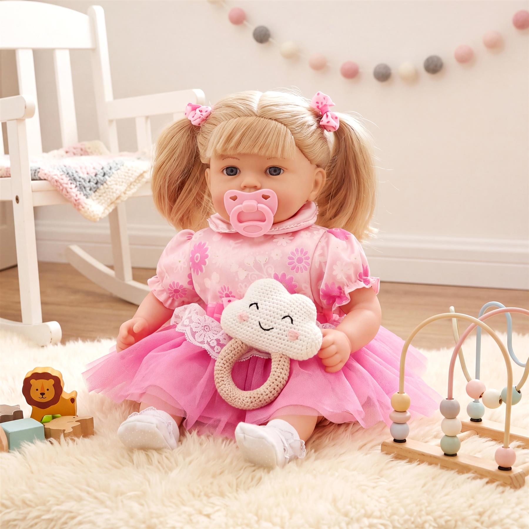 Blonde doll seated on a rug, dressed in pink, with a plush cloud toy and pacifier.