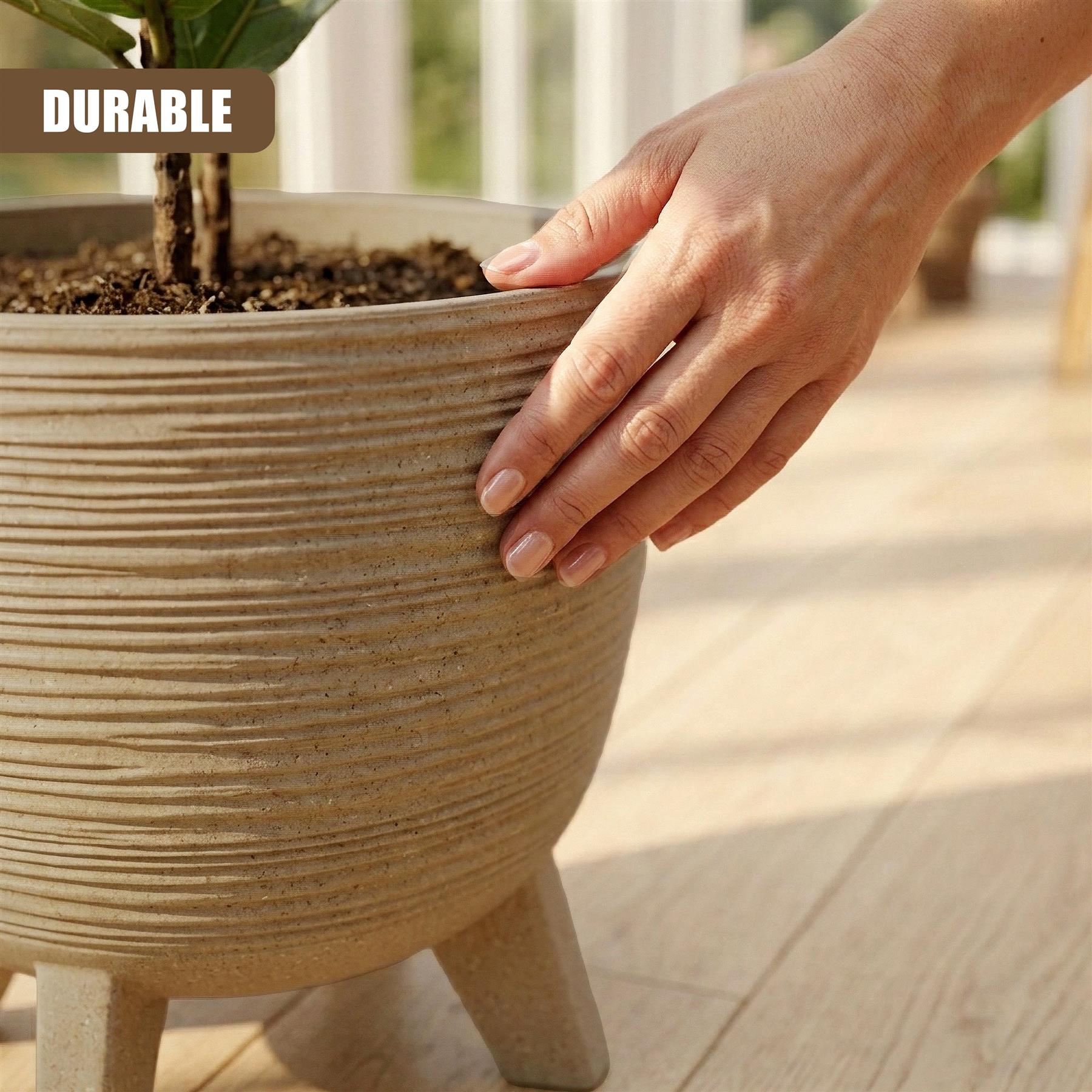 Hand resting on large, fluted brown ceramic flower pot set on short legs.