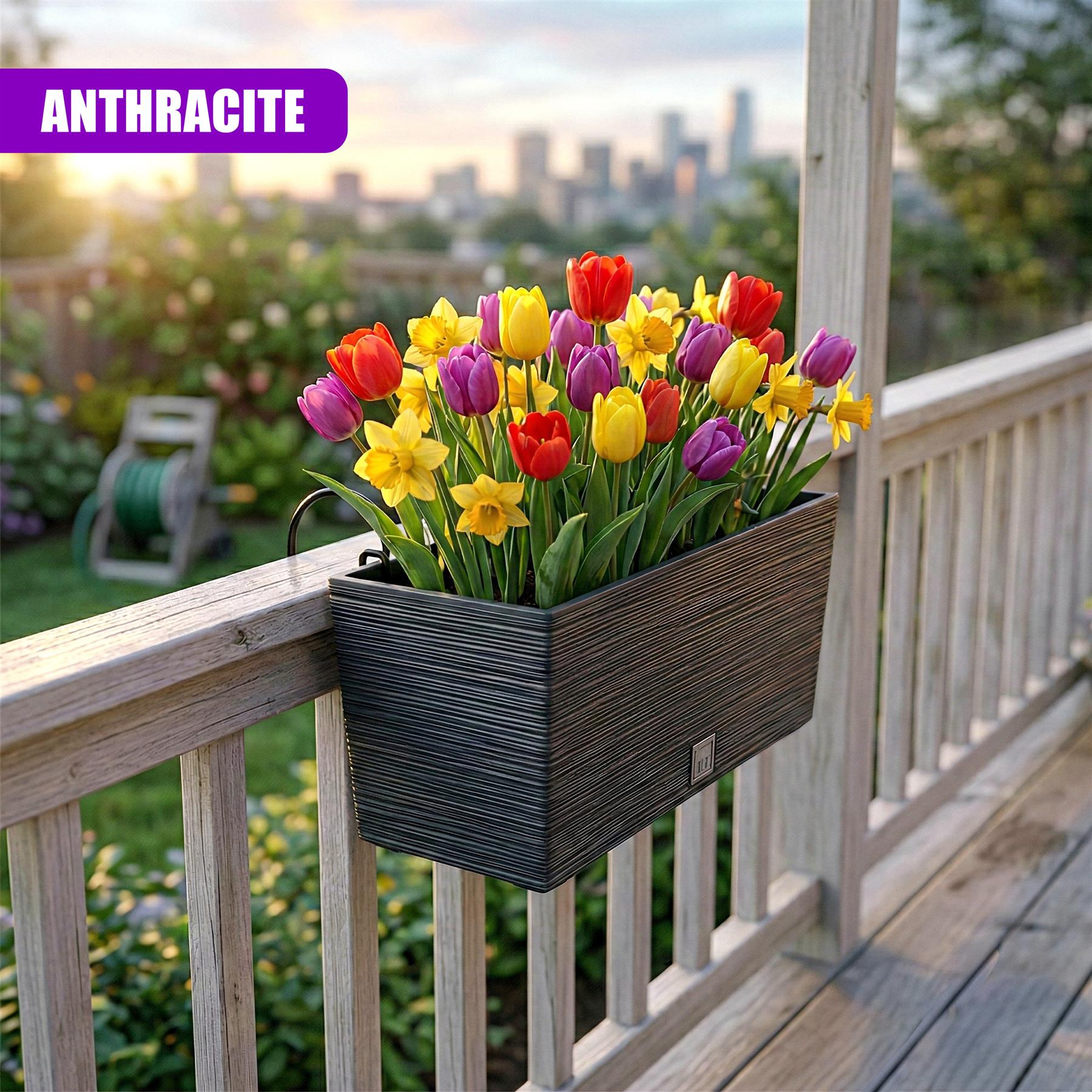 The rectangular anthracite planter holds bright spring flowers on a wooden balcony railing.