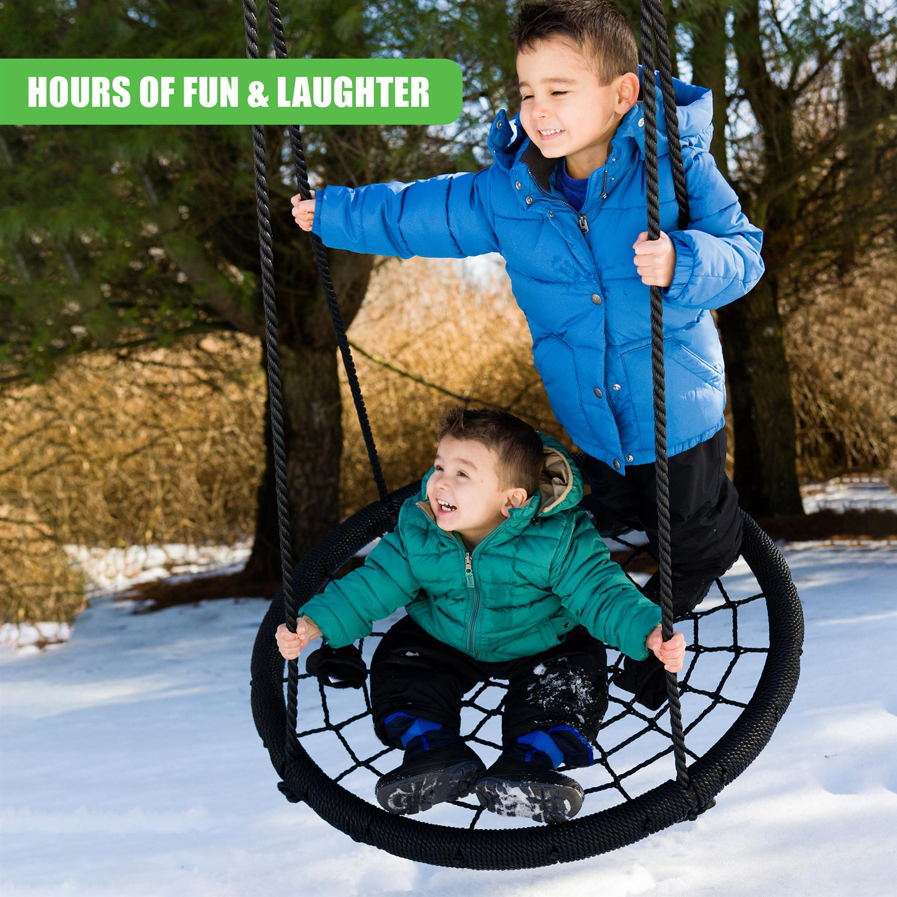 Boys use a black circular nest swing suspended by ropes in a snowy outdoor environment.