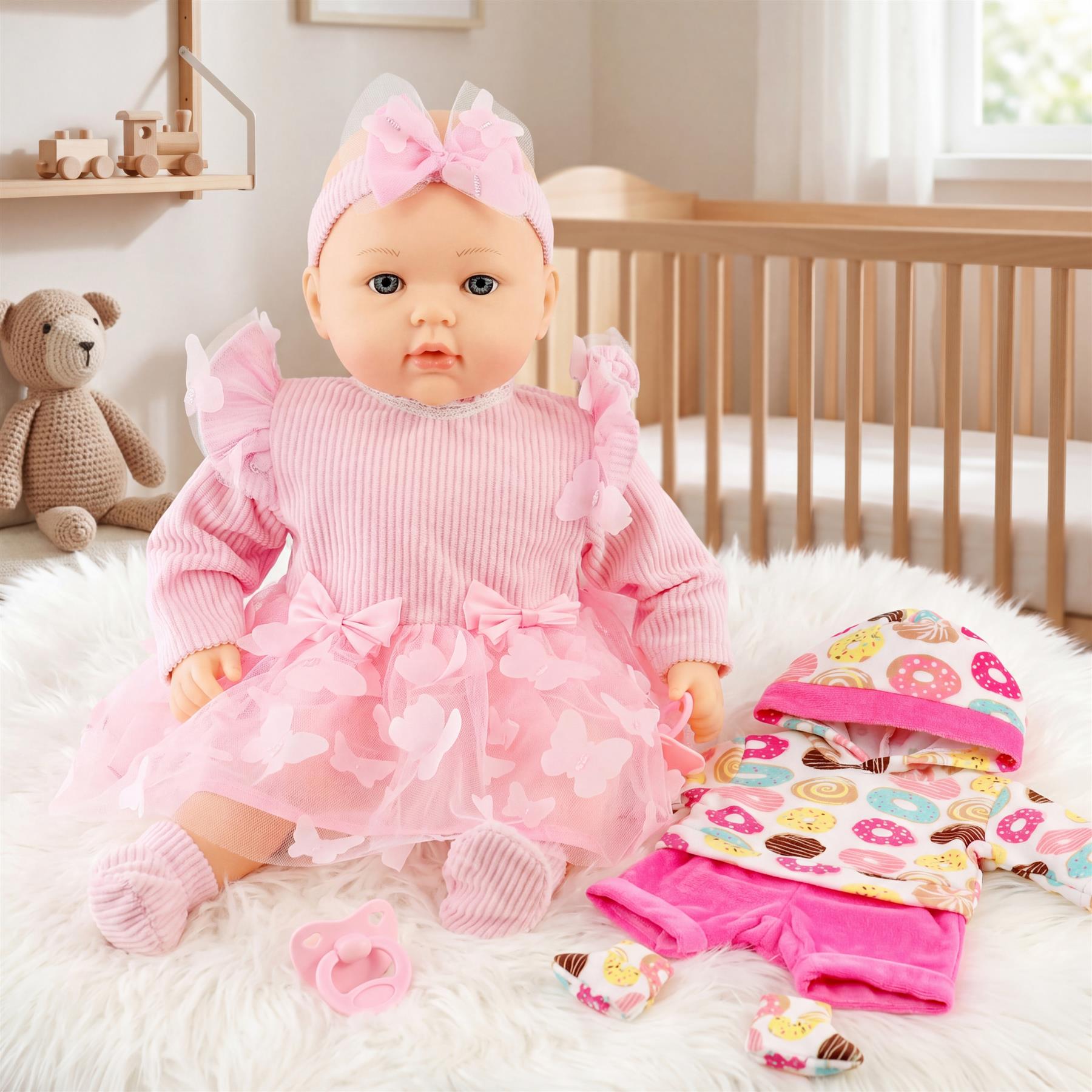 Doll in pink outfit sits on a fluffy rug with accessories, booties, and a teddy bear prop.