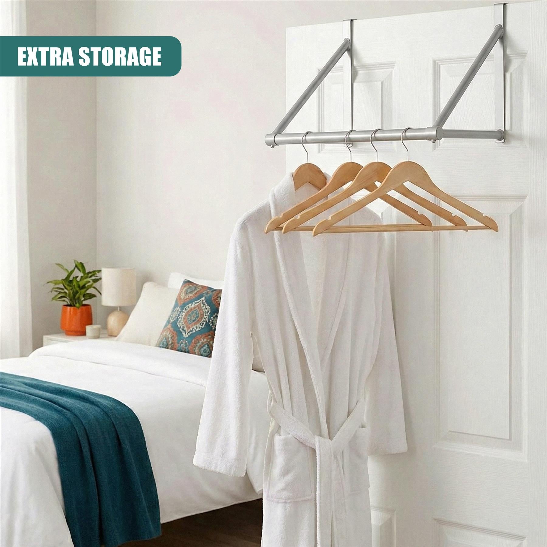A white, wall-mounted garment rack with a silver frame, holding three wooden hangers with white robes hanging from them. The background is a white bedroom with a white bed, a white nightstand, and a white wall. - The Magic Toy Shop