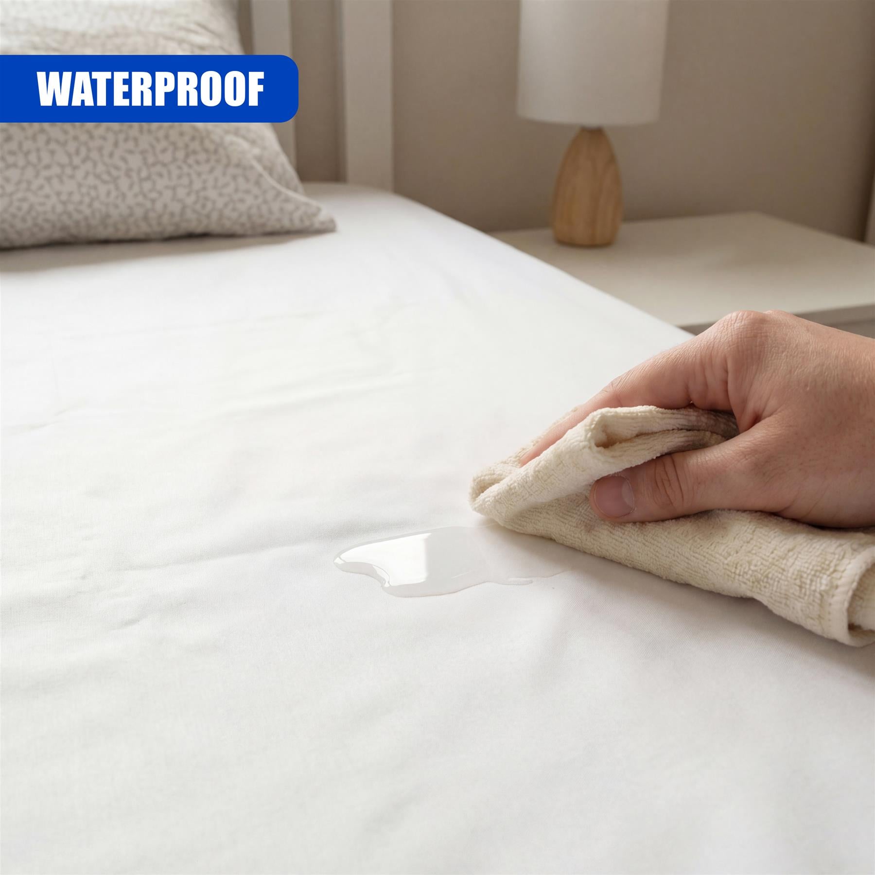 A hand uses a cloth to wipe liquid away from the white fitted bed cover.