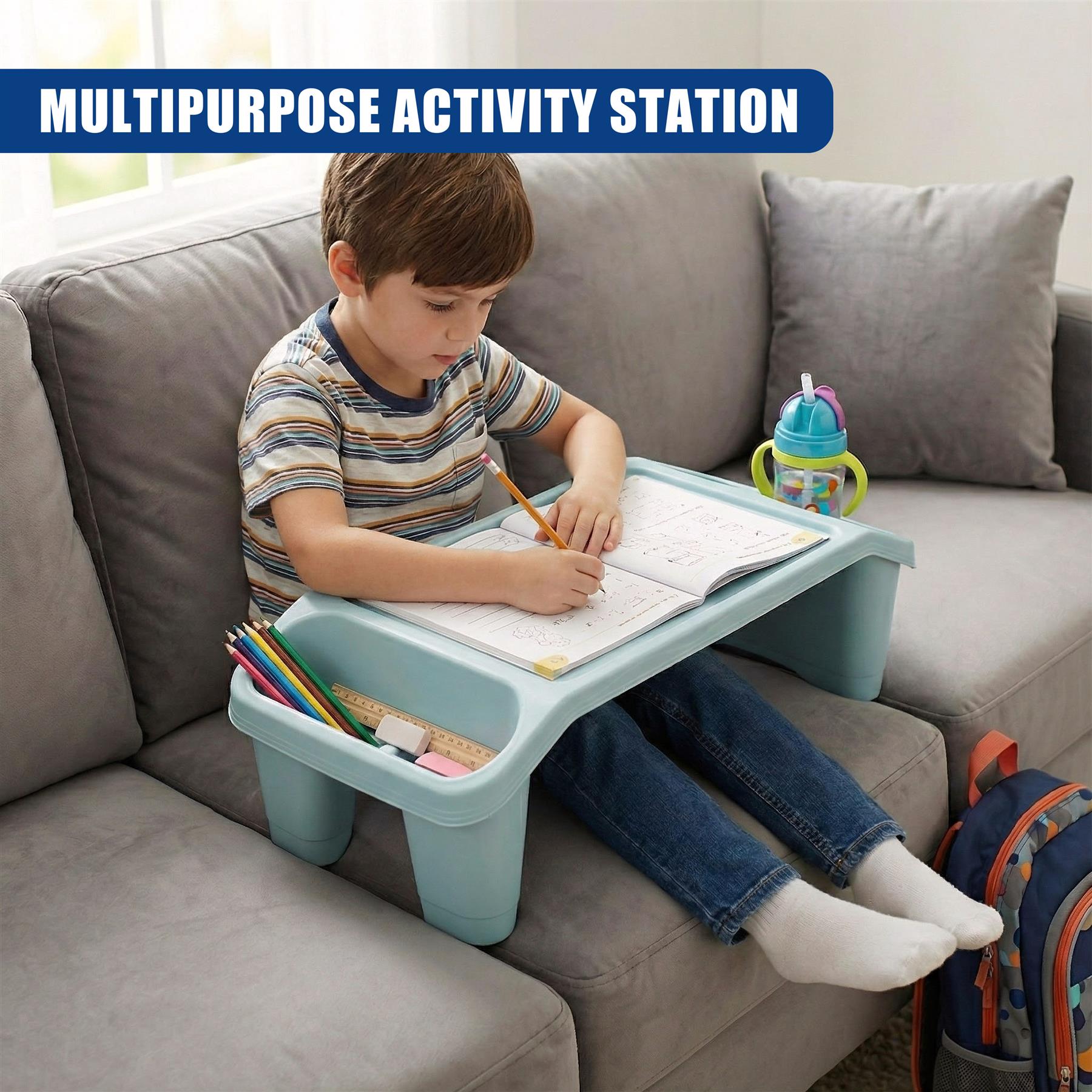 A child sits on a couch, using a portable desk to write in a notebook. The desk has a built-in tray for holding writing supplies and a cup holder. The child is focused on writing, with a book and a cup of juice nearby. - The Magic Toy Shop