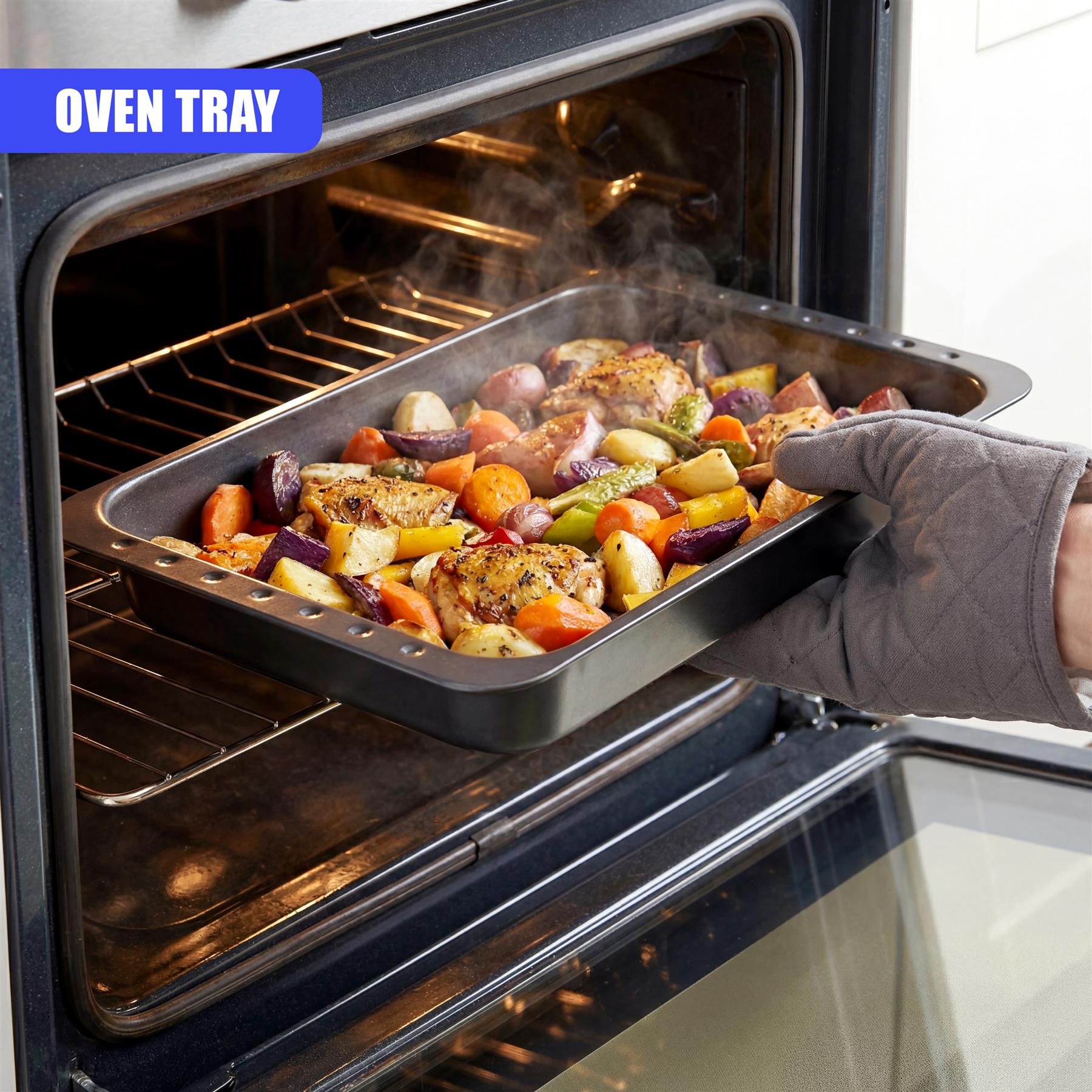 A roasting tin filled with assorted roasted vegetables and seasoned meat pieces inside the open oven.
