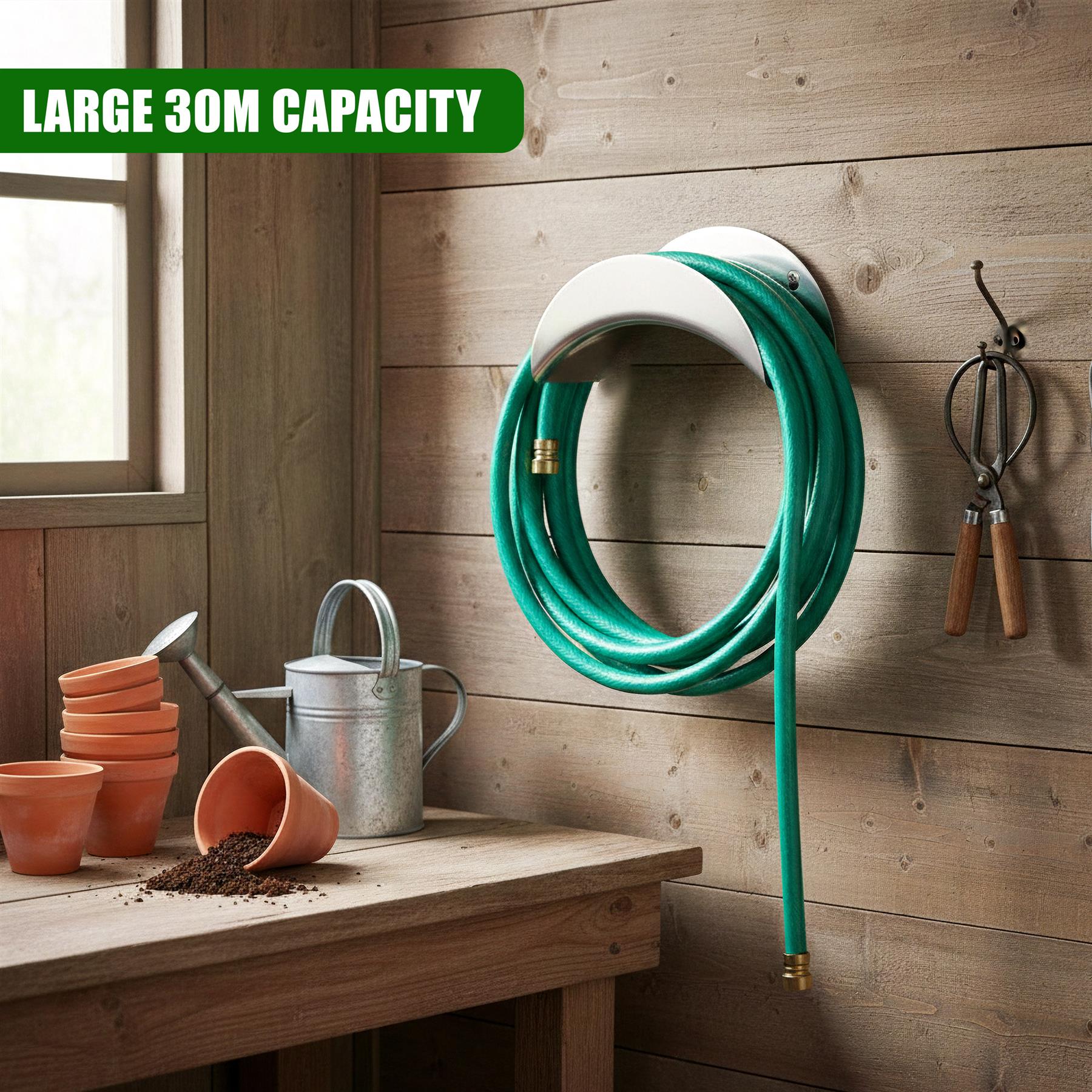White metal curved holder mounts a coiled green garden hose system on a wooden wall.