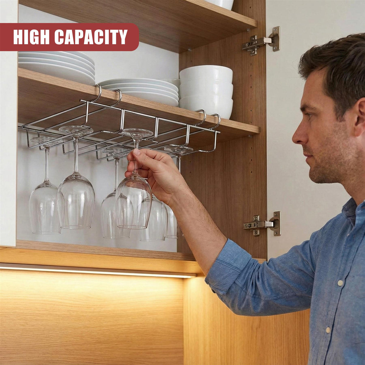 A man installs a GEEZY under shelf wine glass rack on a wooden cupboard shelf