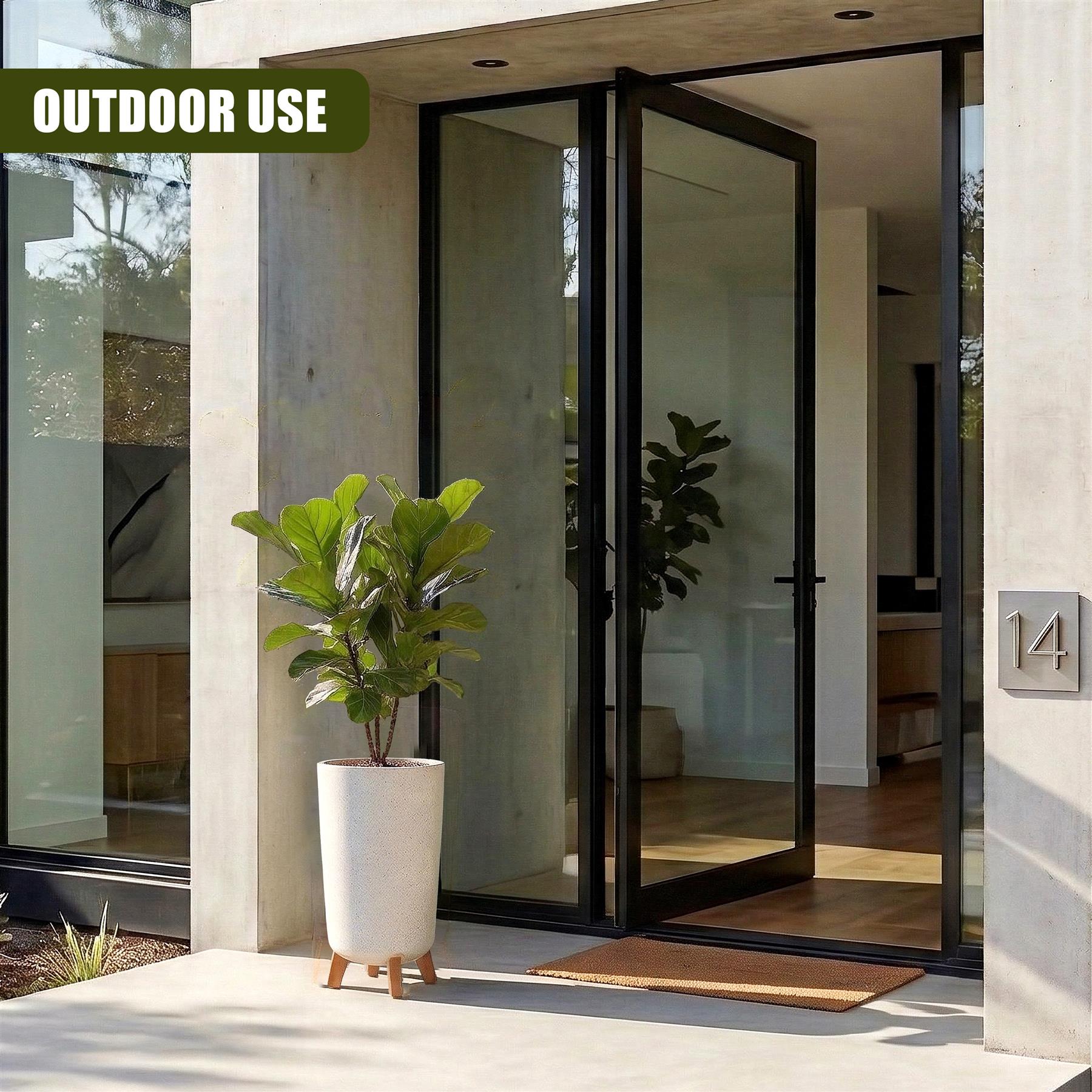 Tall white potted planter with small legs holding a lush green plant near a modern glass entryway door.