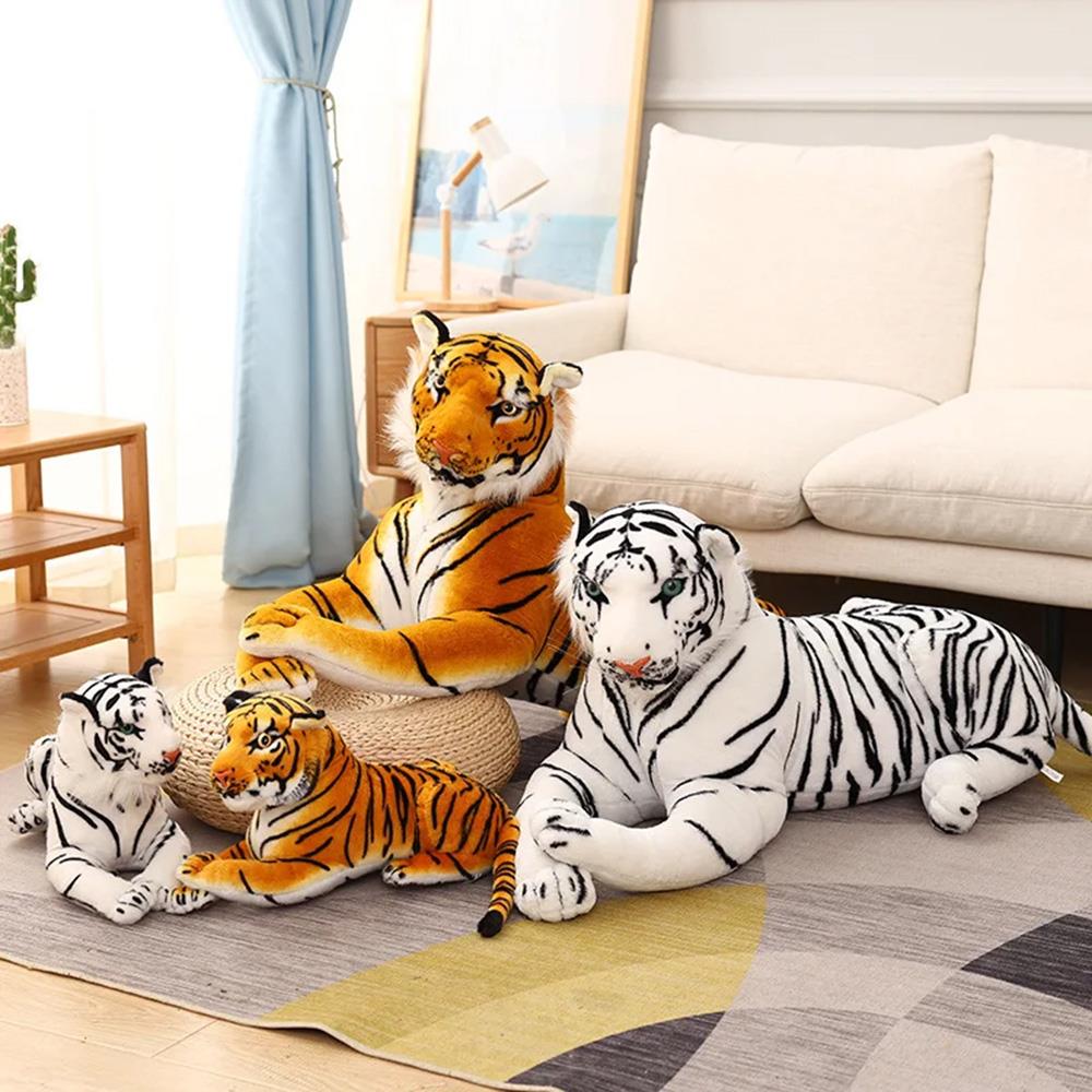 Multiple plush tiger toys are grouped on a rug in front of a cream-colored sofa.