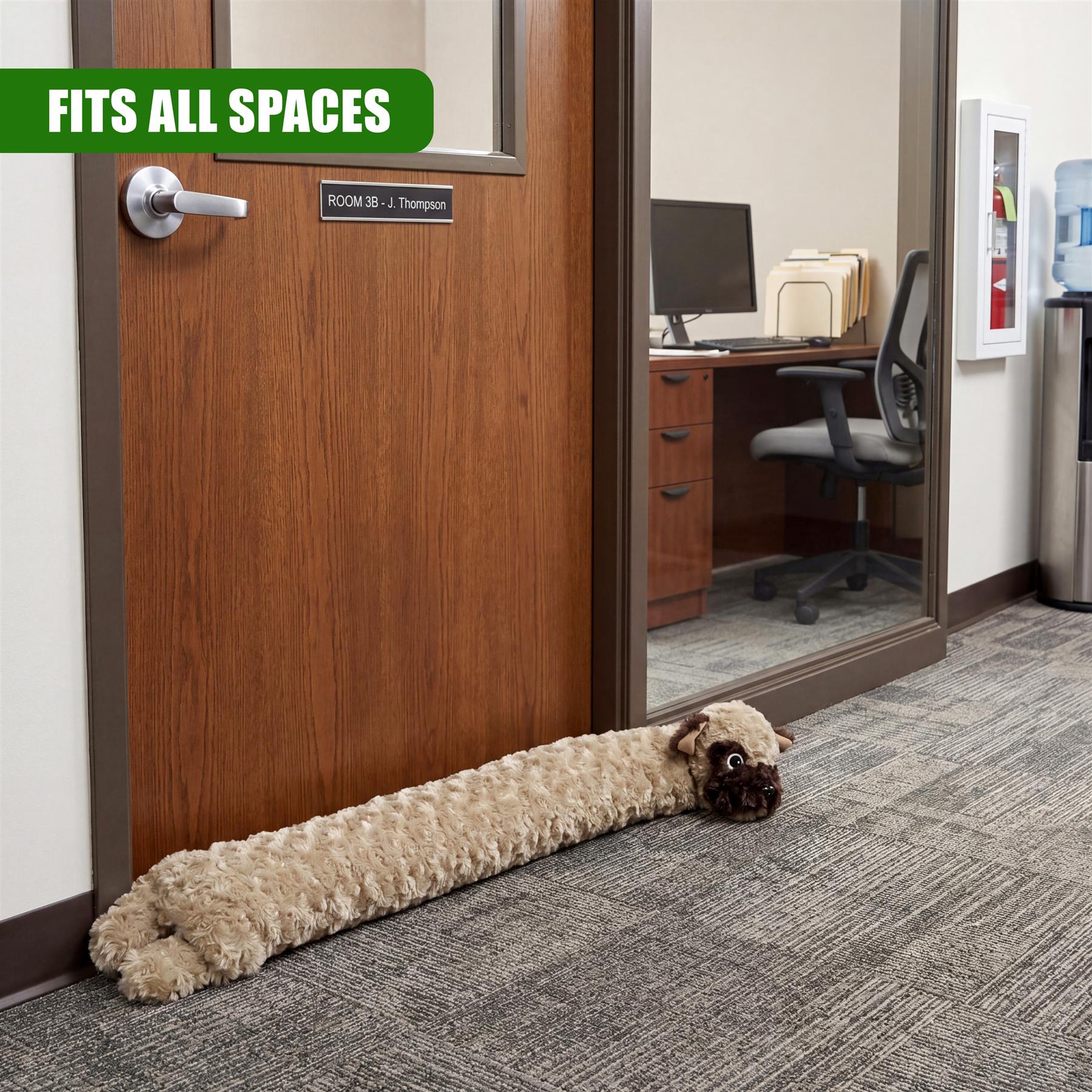 Fluffy dog draught excluder rests on gray carpet before a brown wooden door and mirror.
