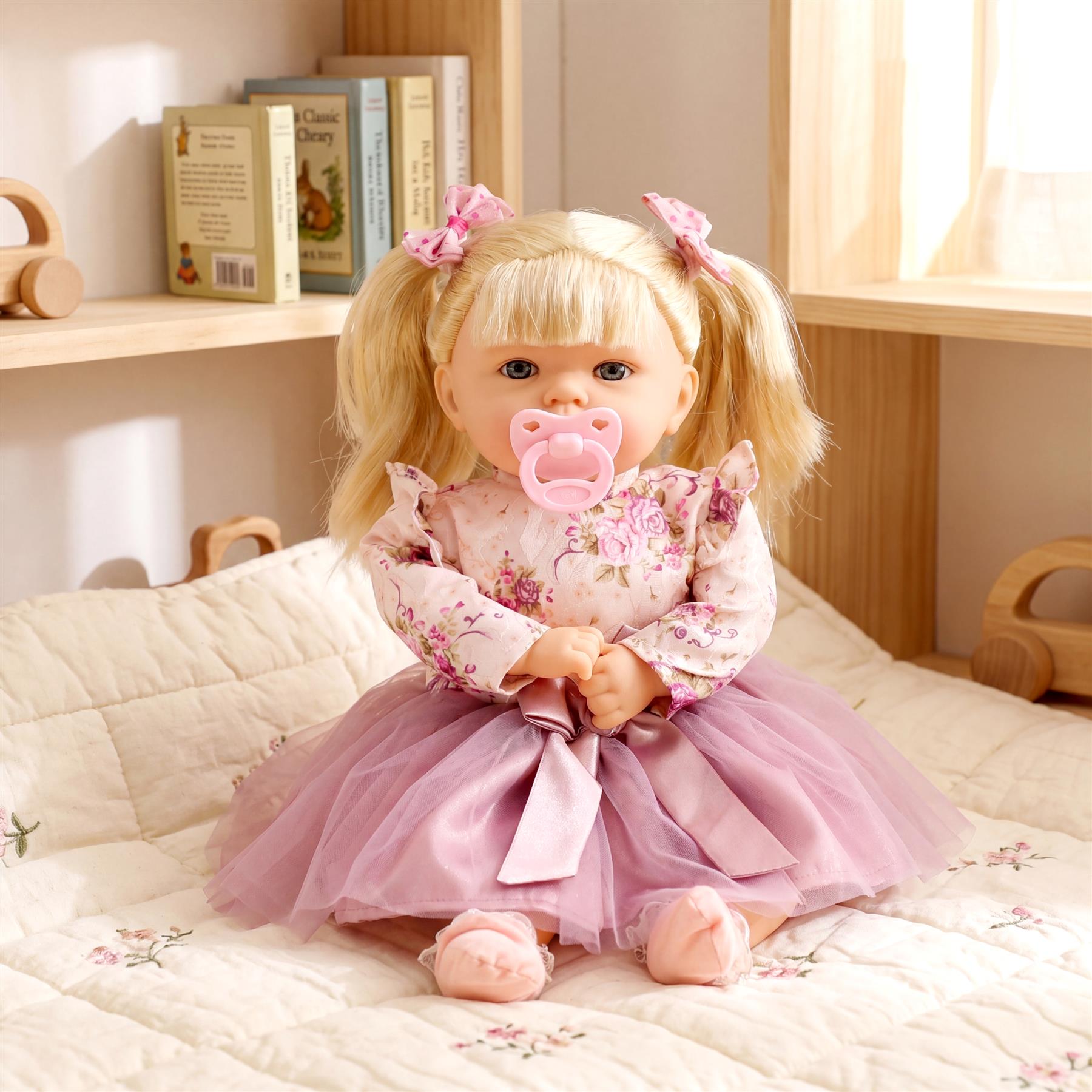 Blonde baby doll wearing a pink floral top and tulle skirt sits on a light patterned blanket.