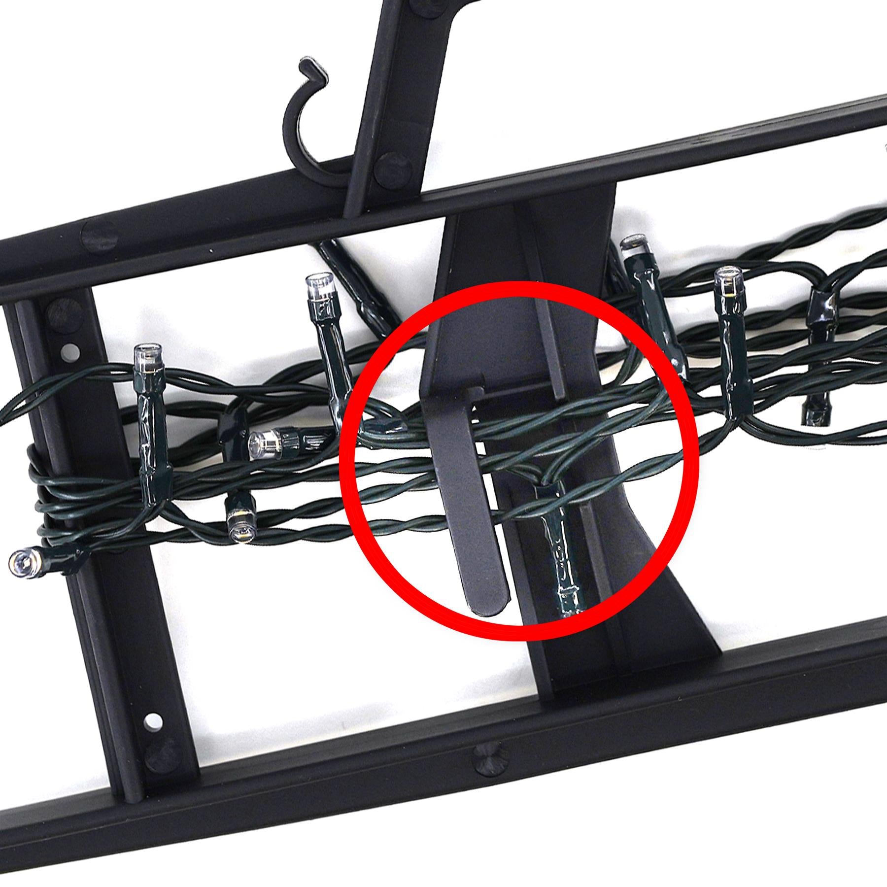 A black metal frame with a black plastic piece in the center, holding a set of black wires and a string of black lights. - The Magic Toy Shop