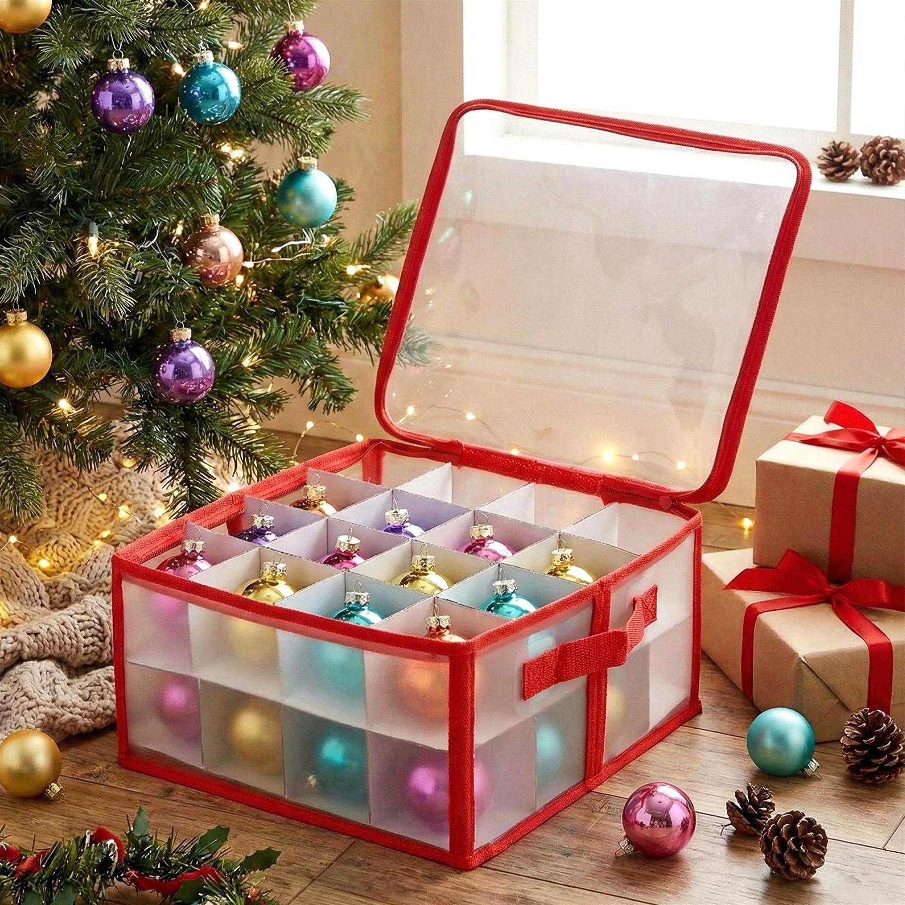A red and clear storage box with a transparent top, containing 12 white compartments, each holding a Christmas ornament, surrounded by Christmas decorations, gifts, and a Christmas tree. - The Magic Toy Shop