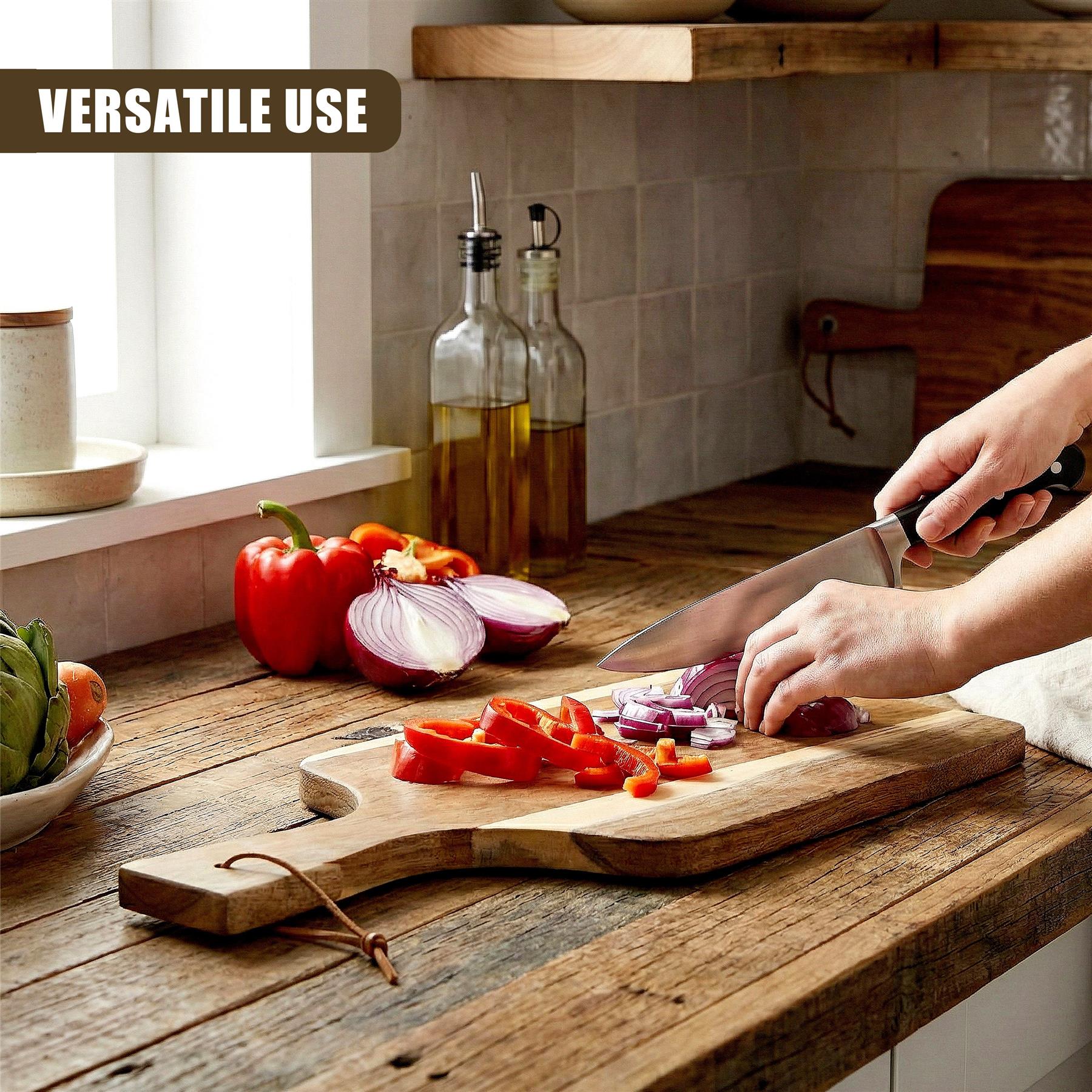 A knife cuts red bell peppers and red onions on a sturdy wooden paddle chopping board.