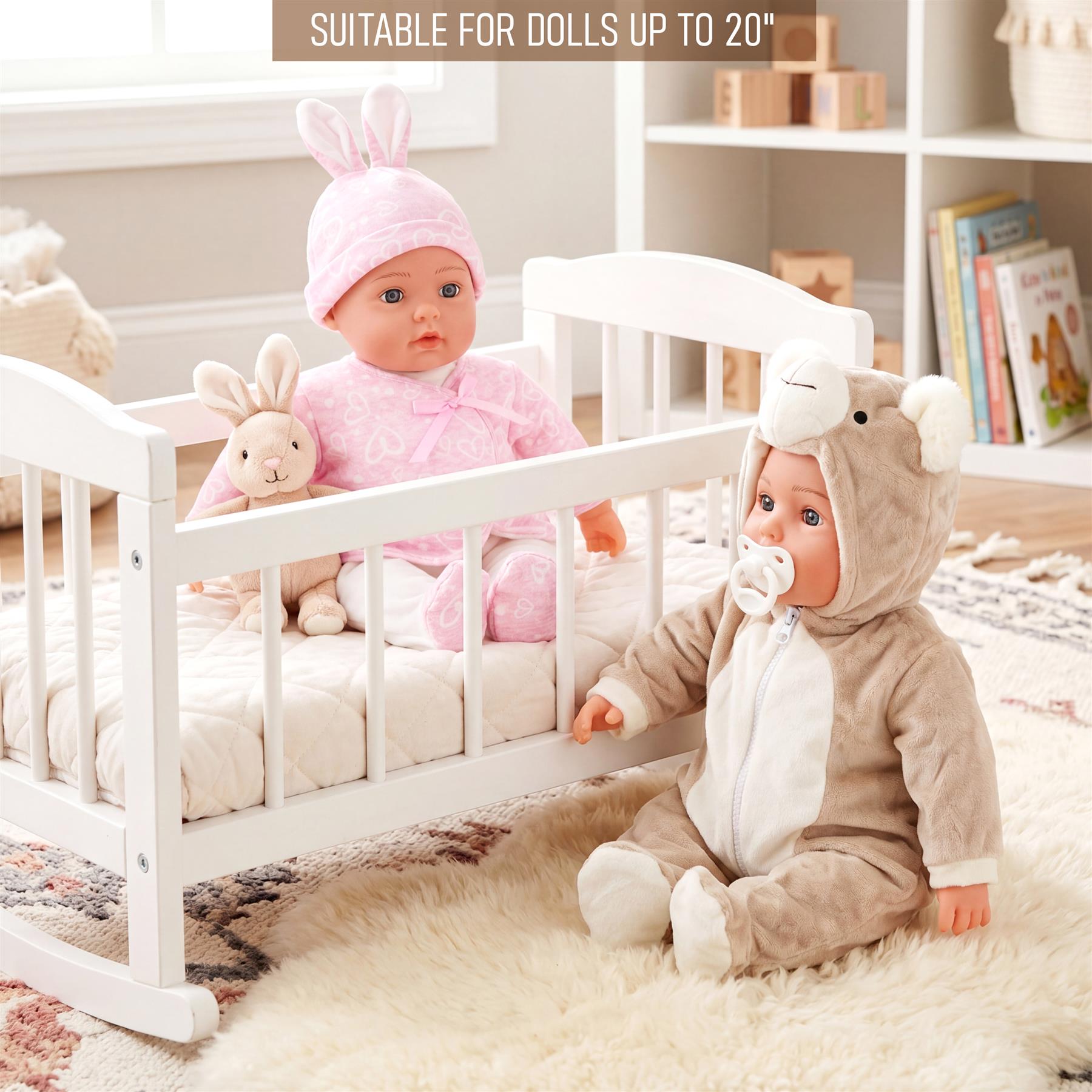 A white crib holds a doll in a pink bunny outfit next to a bear-themed doll.