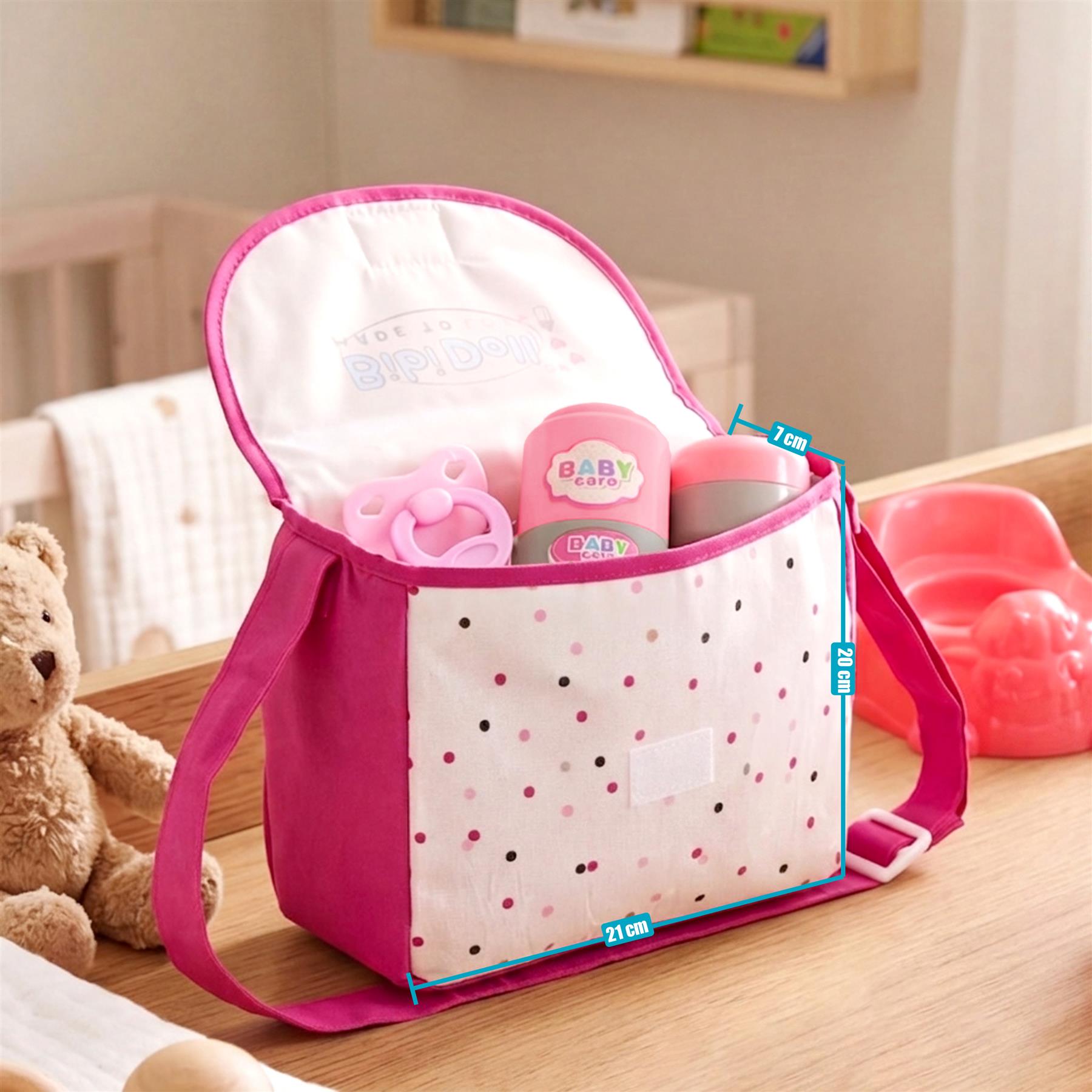 Open pink fabric changing bag with polka dots, containing baby bottles and plastic accessories.
