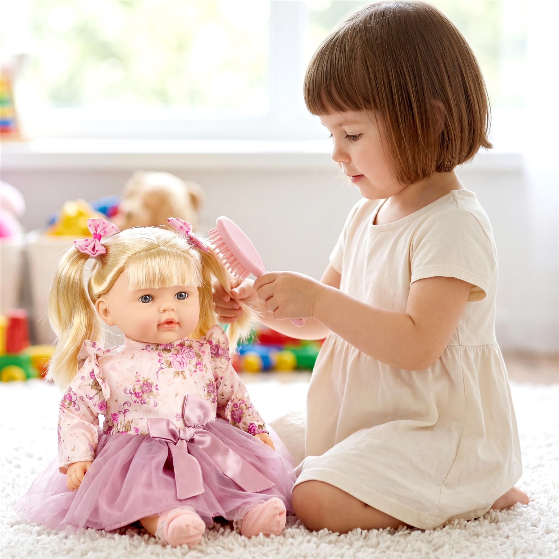 A young girl brushes the blonde hair of a large doll dressed in pink, sitting on a rug.
