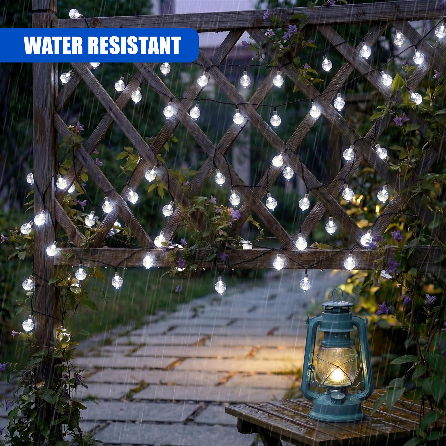 Illuminated crystal string lights hang on a wooden trellis over a wet garden pathway.