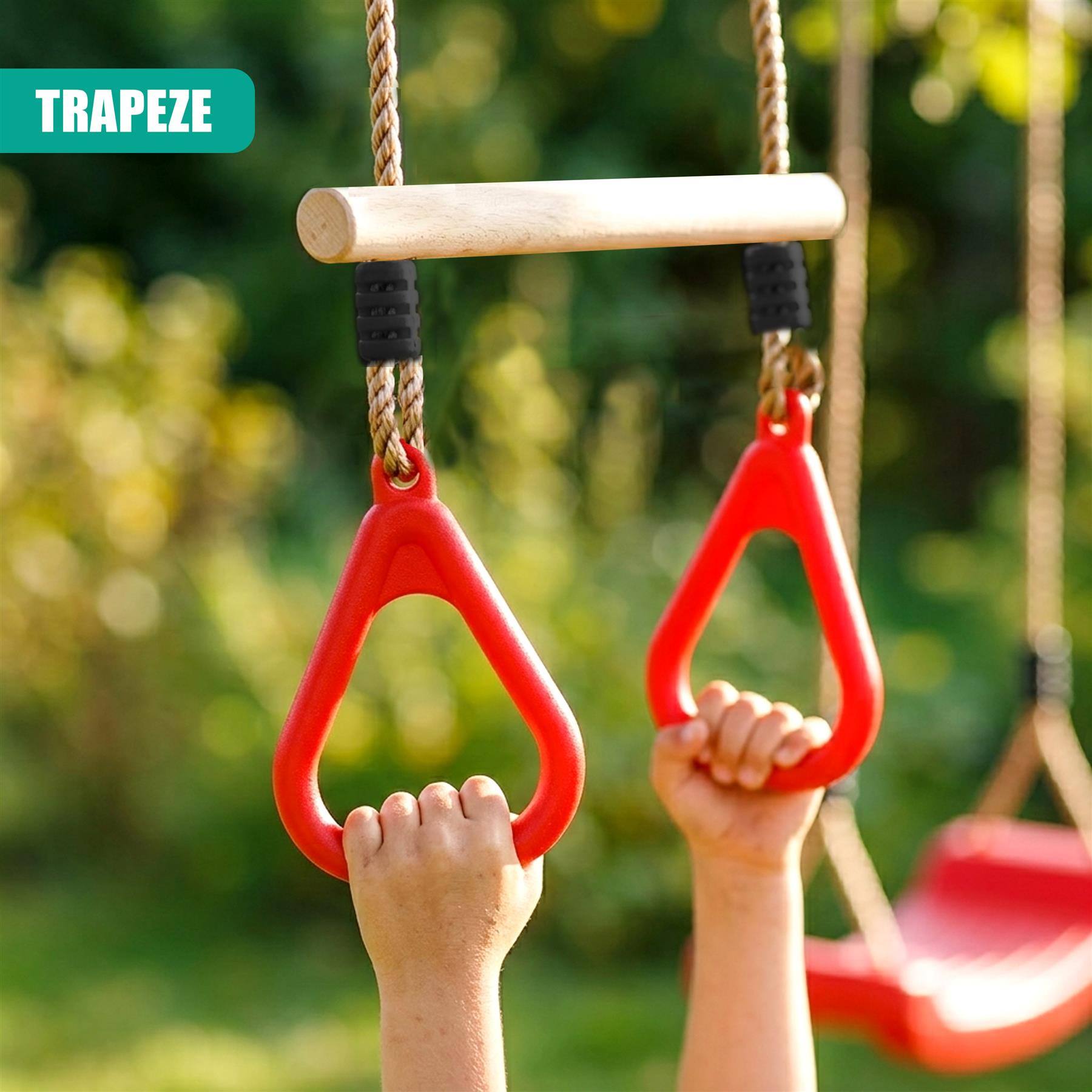 Two red trapeze rings and a wooden bar hang from ropes for children to grasp outdoors.