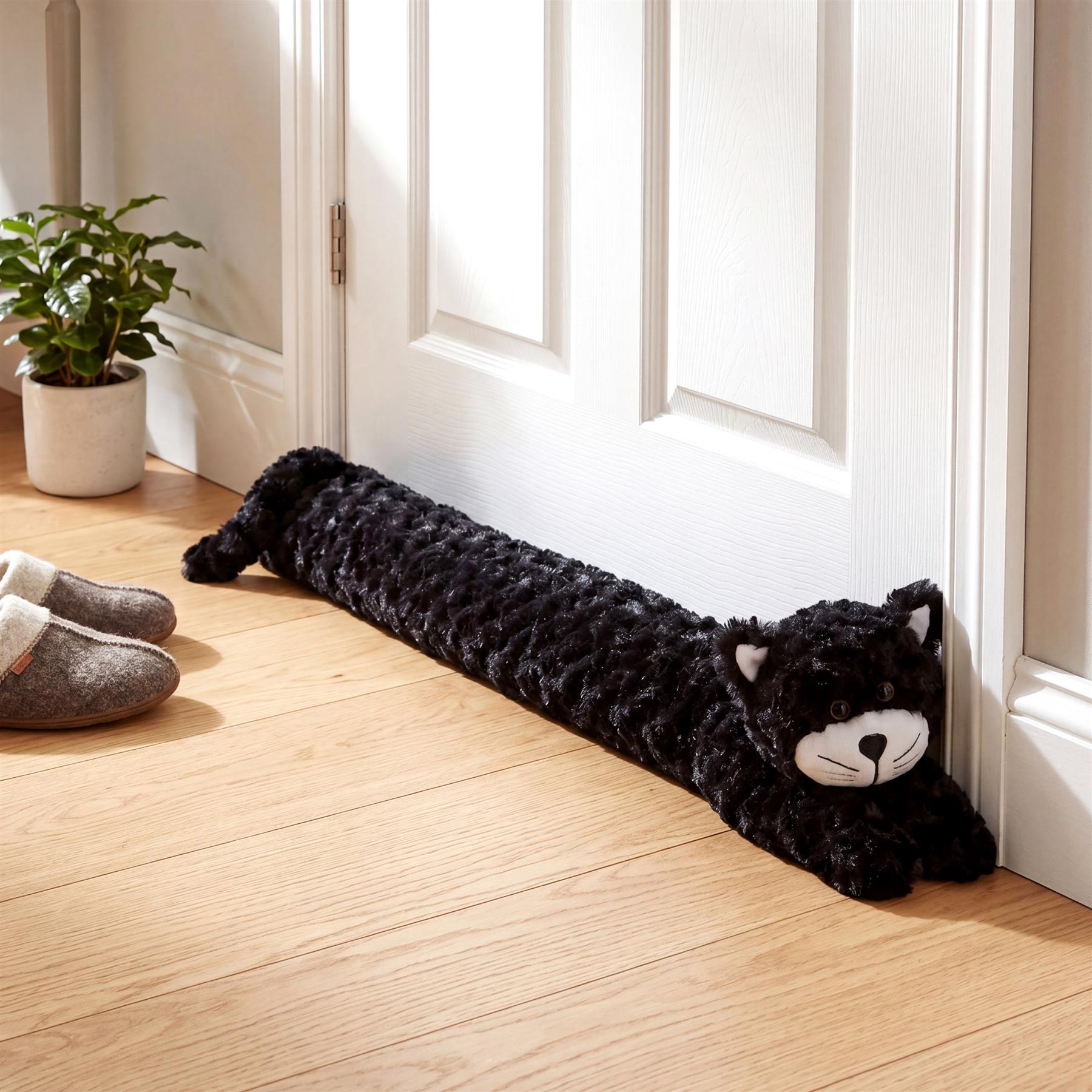 Black faux fur cat draught excluder positioned at the base of a white interior door.
