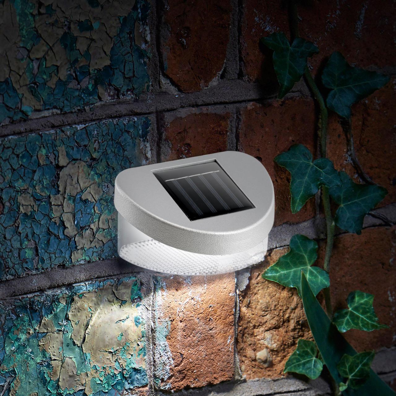A square solar lantern is mounted on a textured brick surface with green ivy vines.