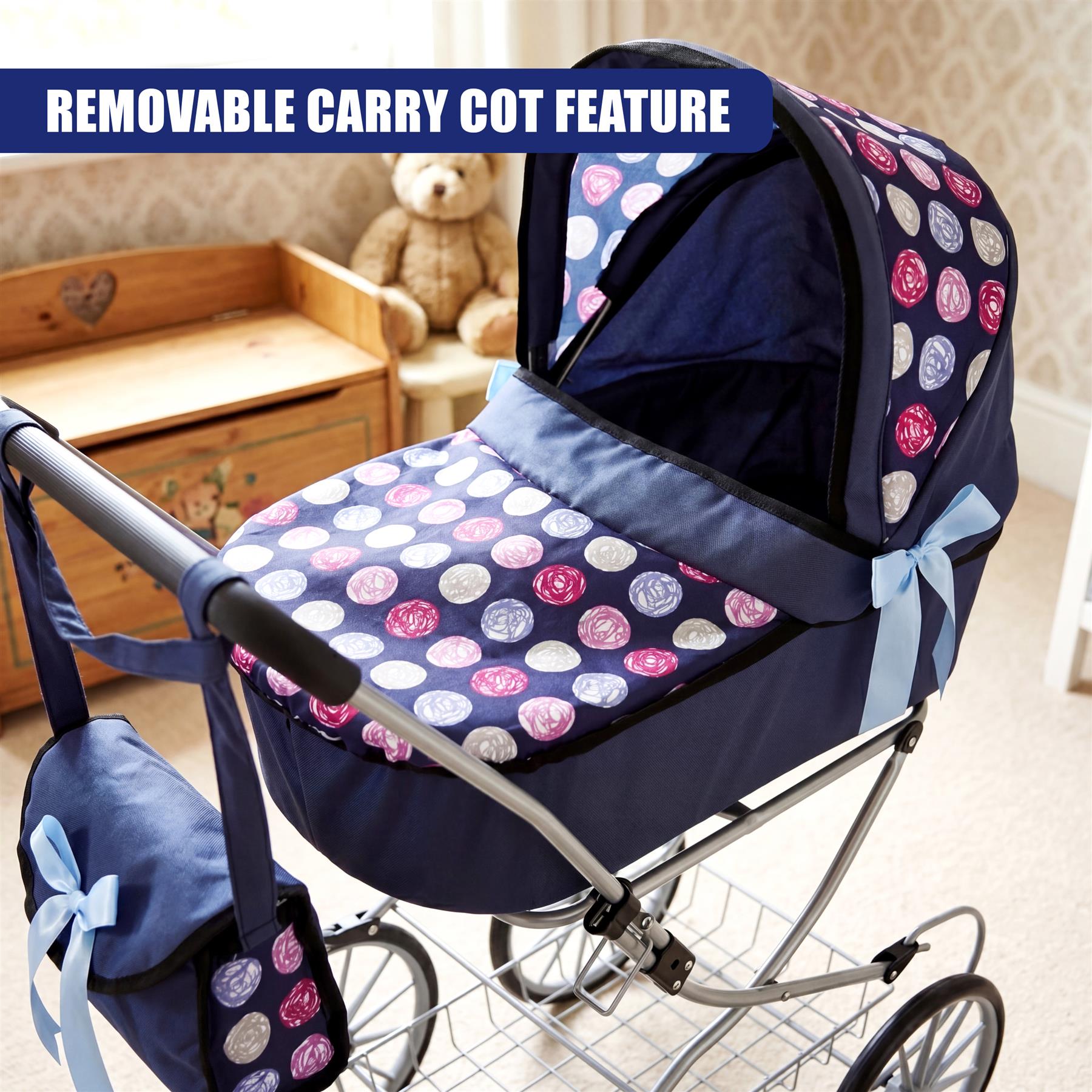 Navy blue and patterned doll pram shown with attached basket, sitting next to a wooden crib.