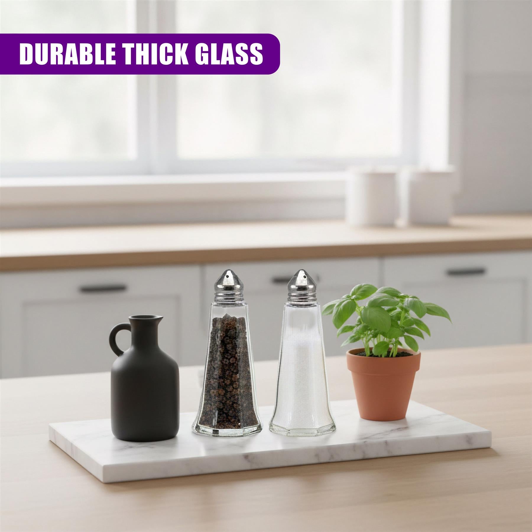 Three salt and pepper shakers and a potted plant sit on a marble tray.