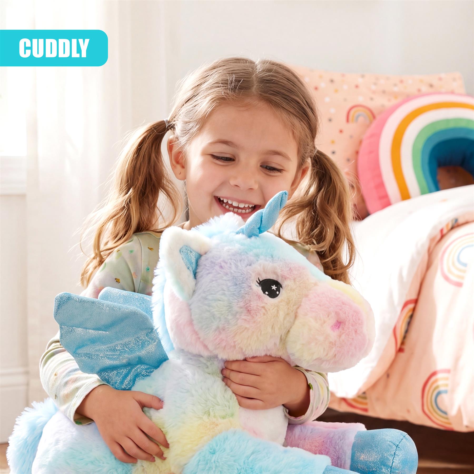 Girl embraces soft, multicolored unicorn plush toy near a patterned bed and pillows.
