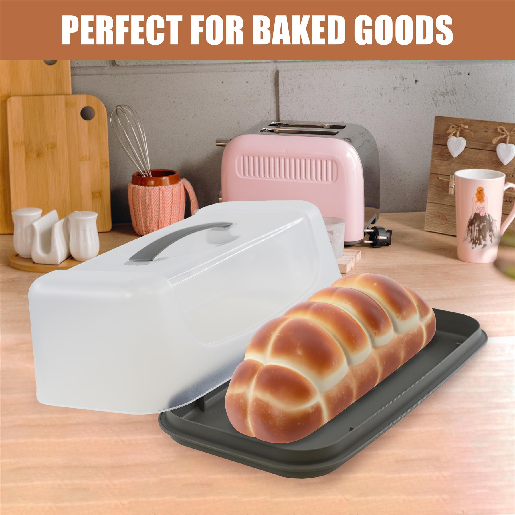 White rectangular cake carrier with handle and lid sits on a dark tray with golden bread.