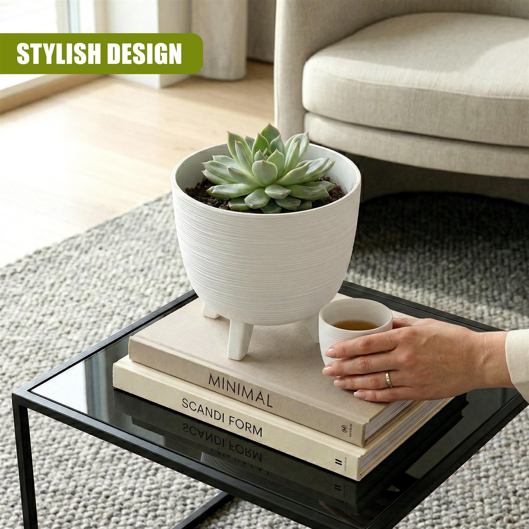 White potted planter with legs containing a succulent sits atop a stack of books.